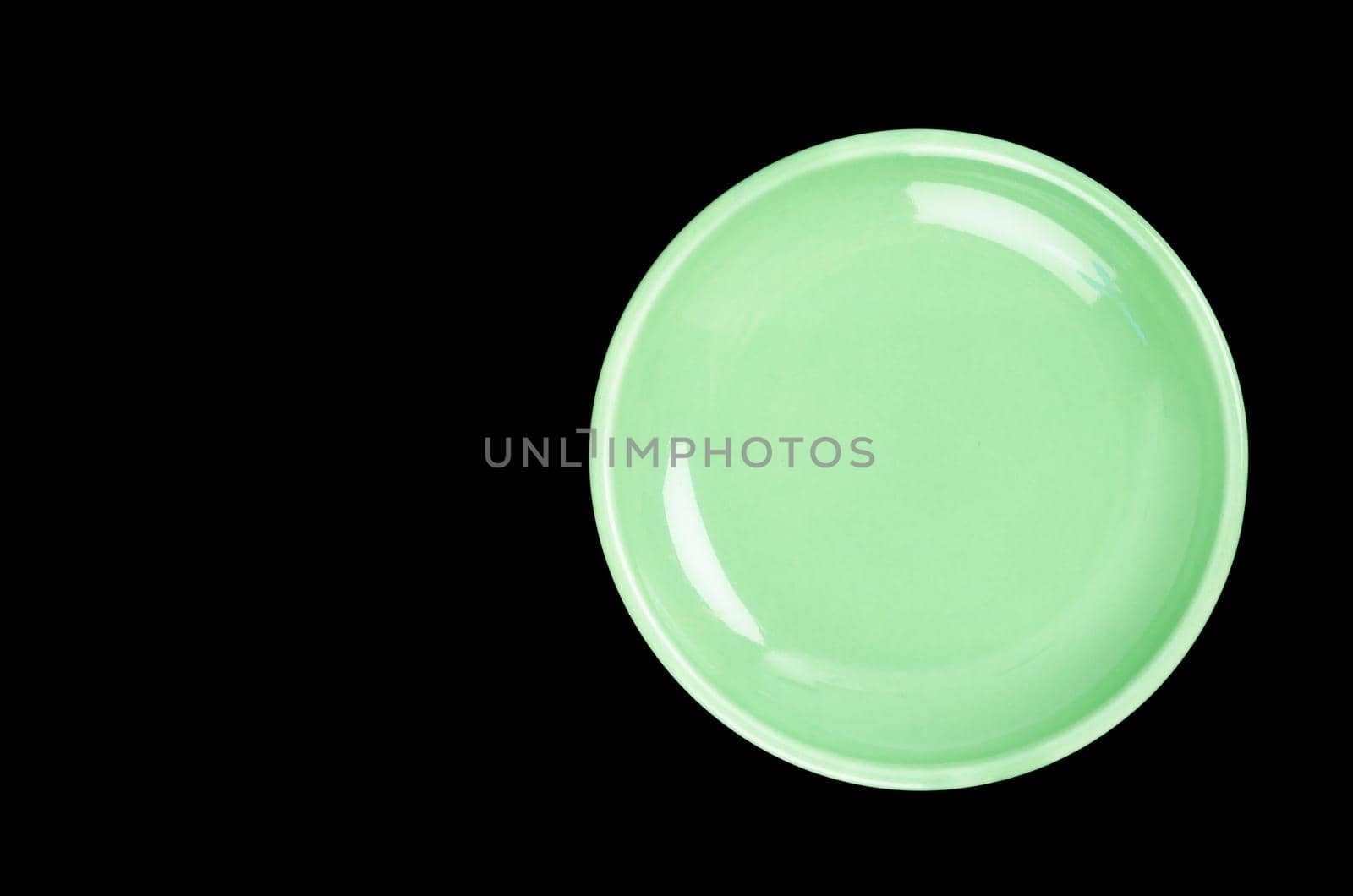 Empty green ceramic plate on black background