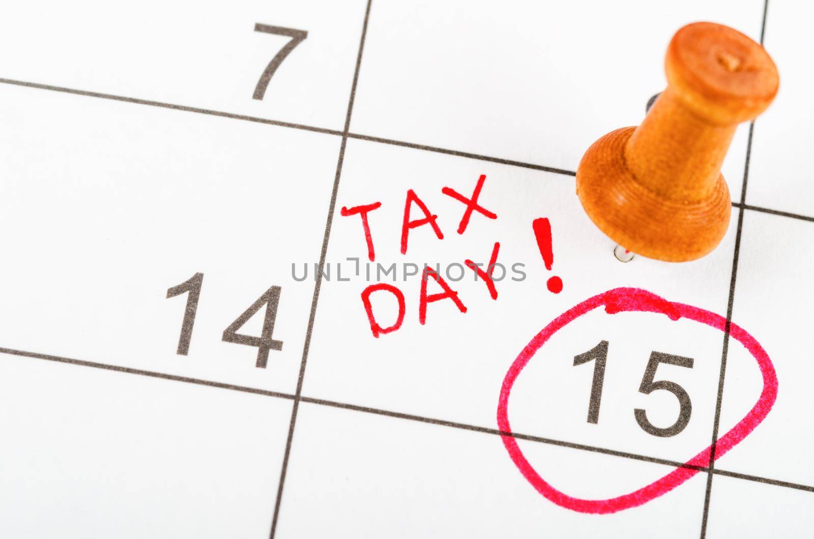 Handwritten Tax day for reminde apointment with wooden pin on a calendar.