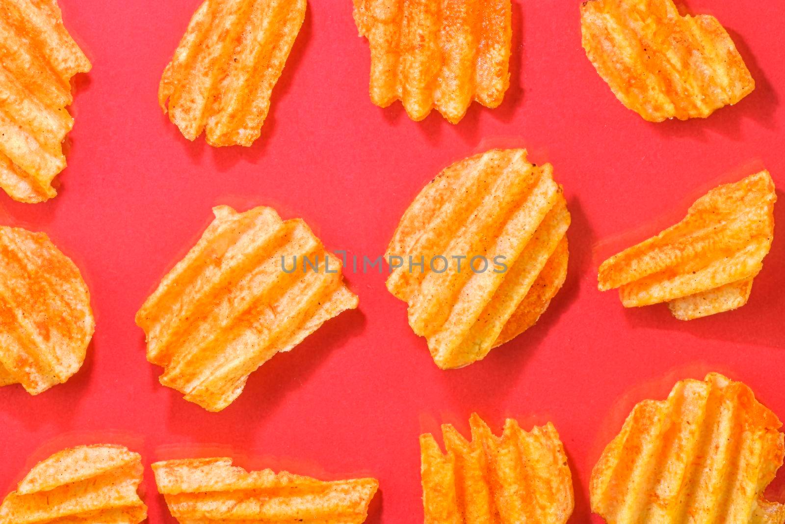 Ribbed potatoes snack with pepper on red background. Ridged potato chips on red background. Set of potato chips. Flat lay. Close-up.