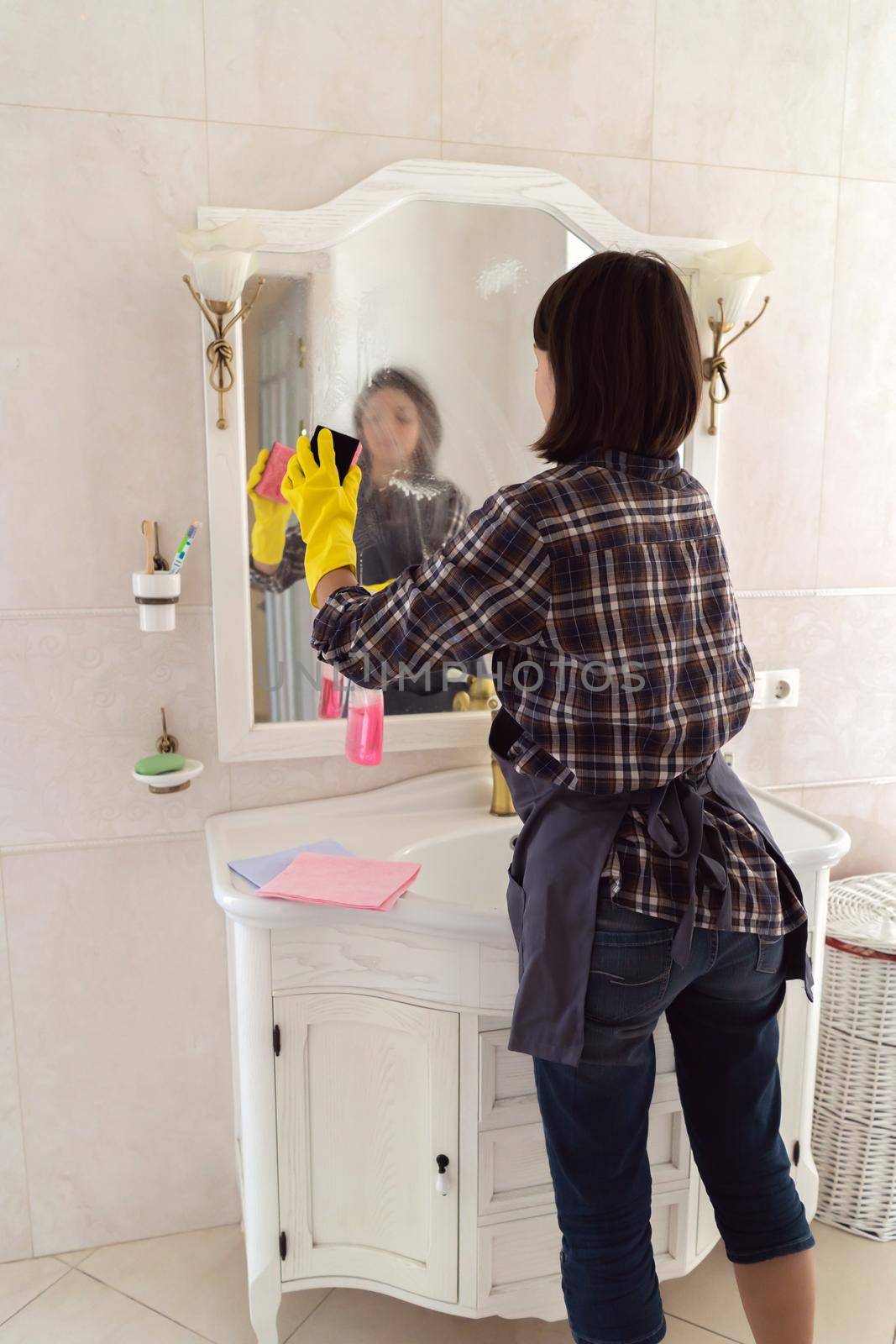 Young woman is washing mirror in the bathrom. by africapink