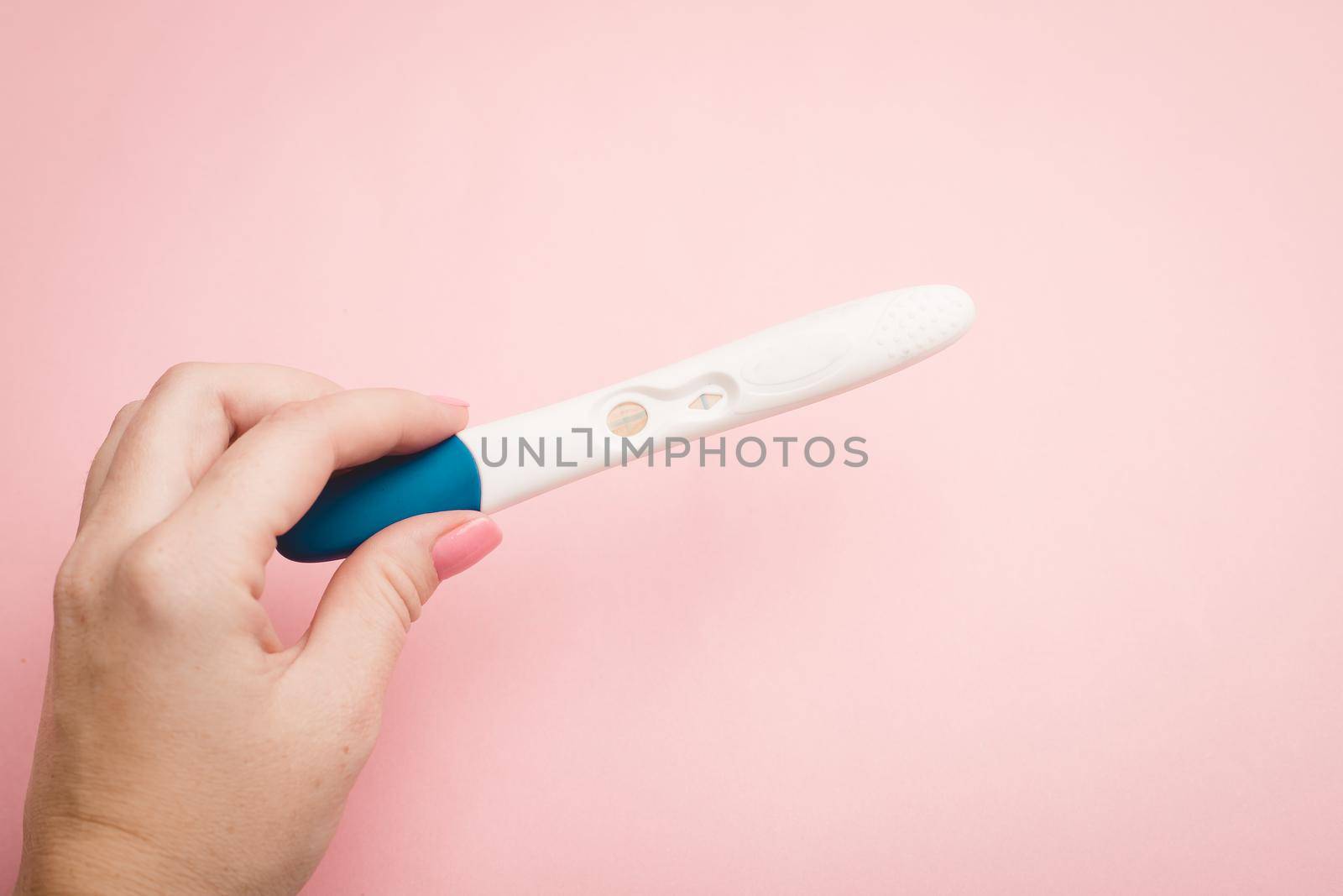 Pregnancy test in hand on a pink background . Positive test. Pregnancy copy space. Motherhood