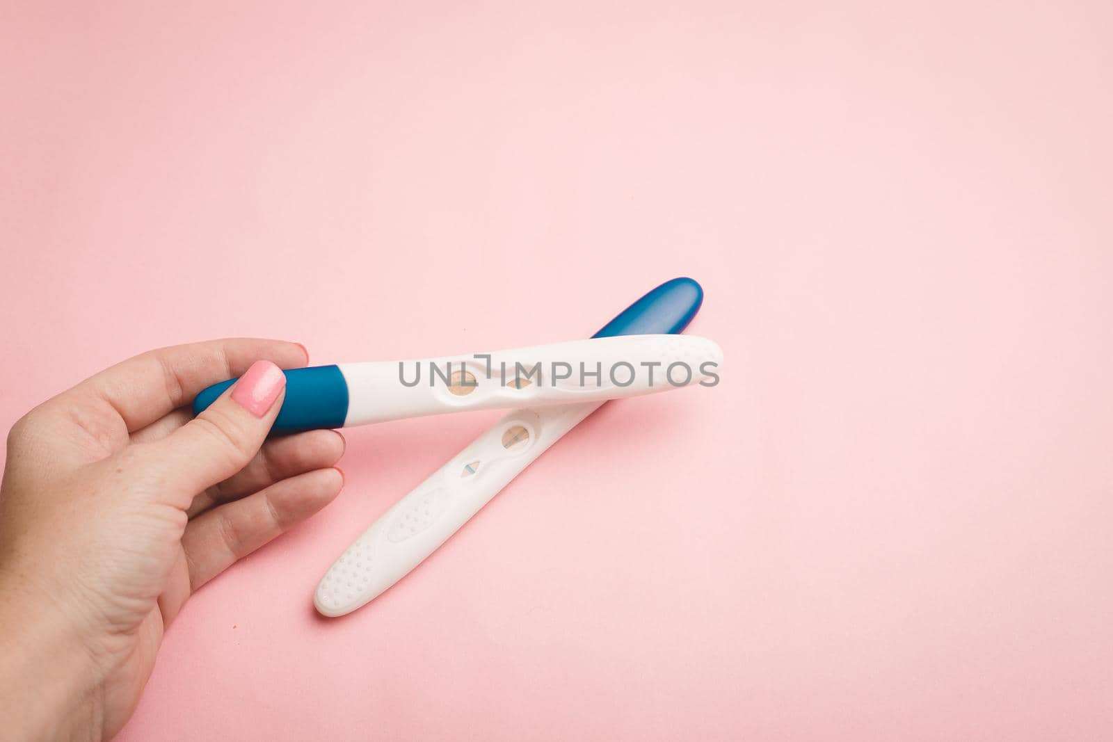Pregnancy test in hand on a pink background . Positive test. Pregnancy copy space. Motherhood