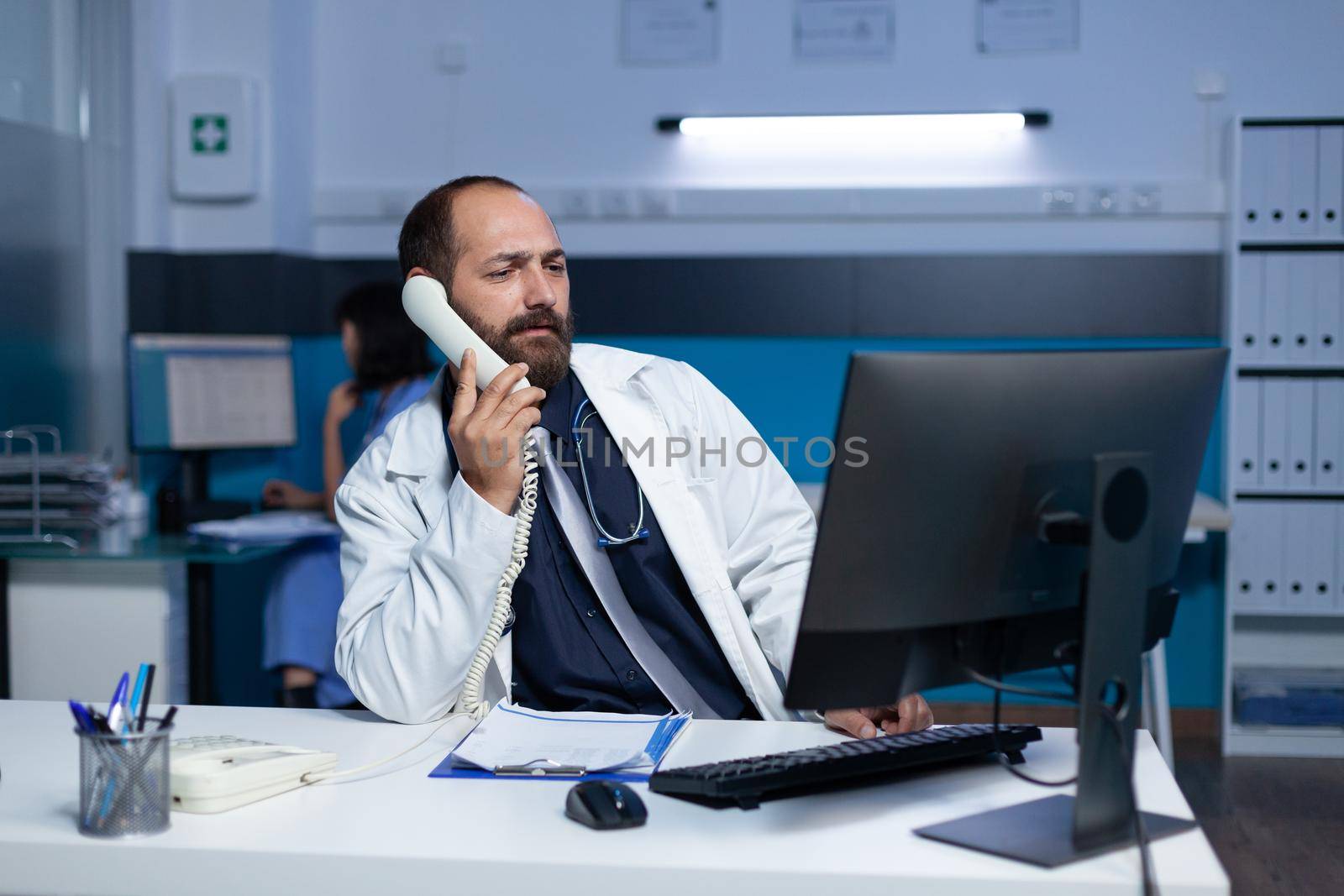 Medic using landline phone for remote communication overtime by DCStudio