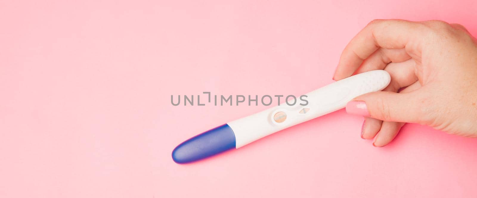 Pregnancy test in hand on a pink background . Positive test. Pregnancy copy space. Motherhood