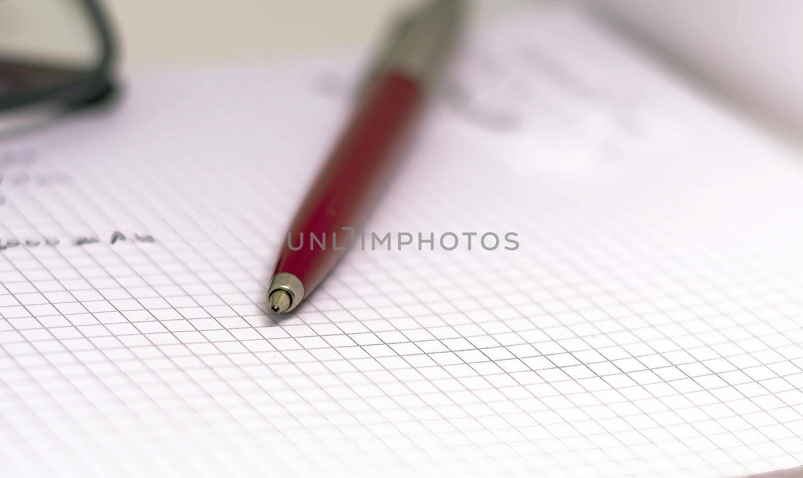 Red pen on an open squared notebook. by rarrarorro