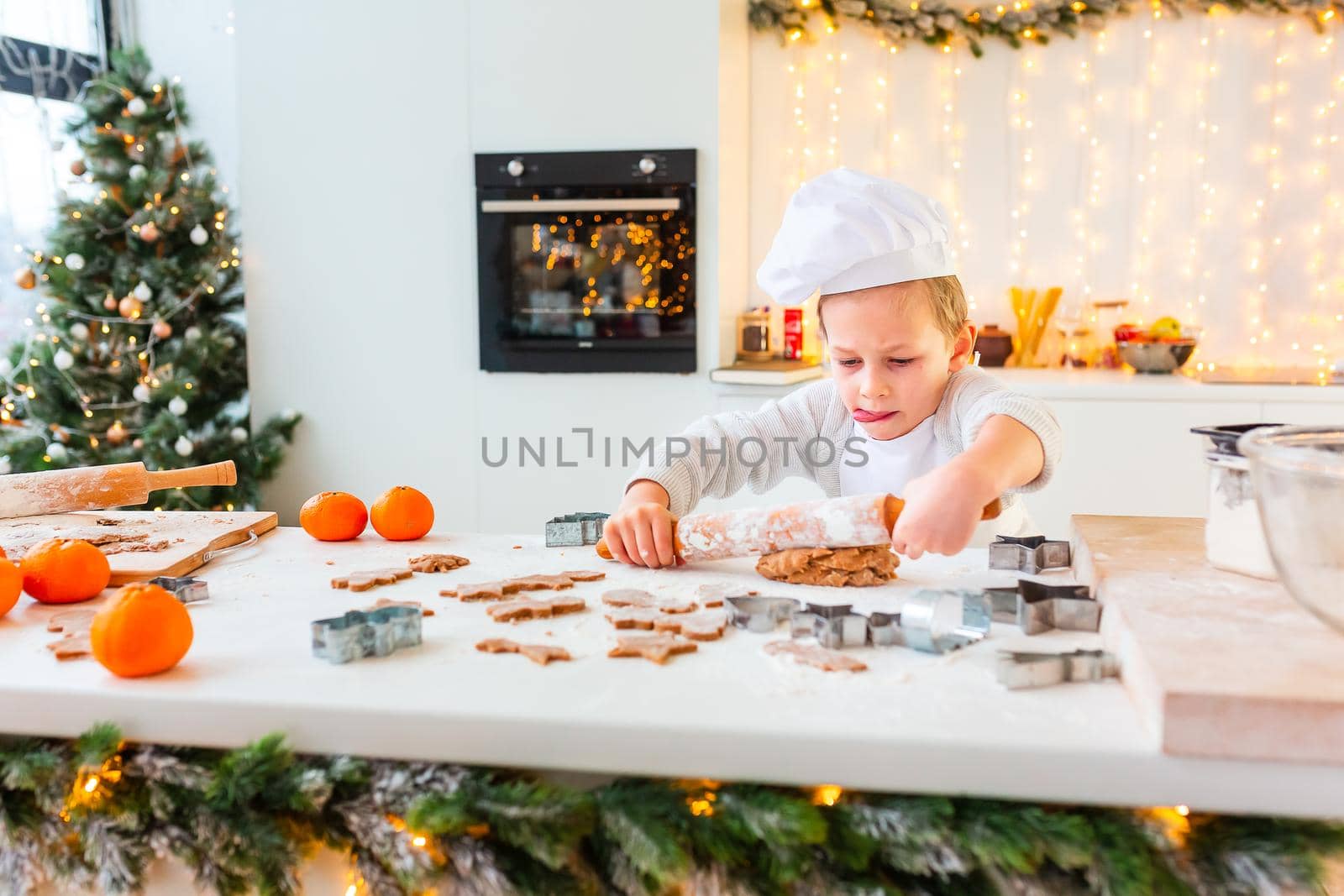 Cute little boy making gingerbread, cutting cookies of gingerbread dough. Christmas bakery. Festive food, cooking process, family culinary, Christmas and New Year traditions concept