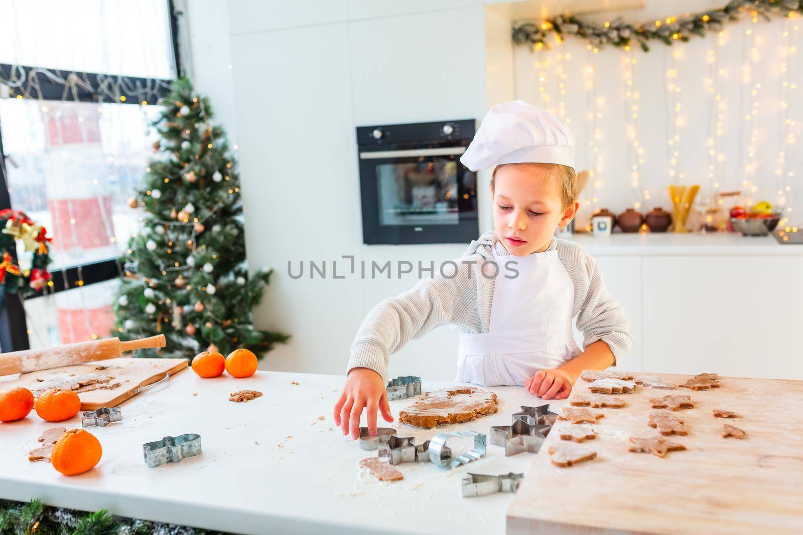 Cute little boy making gingerbread, cutting cookies of gingerbread dough. Christmas bakery. Festive food, cooking process, family culinary, Christmas and New Year traditions concept