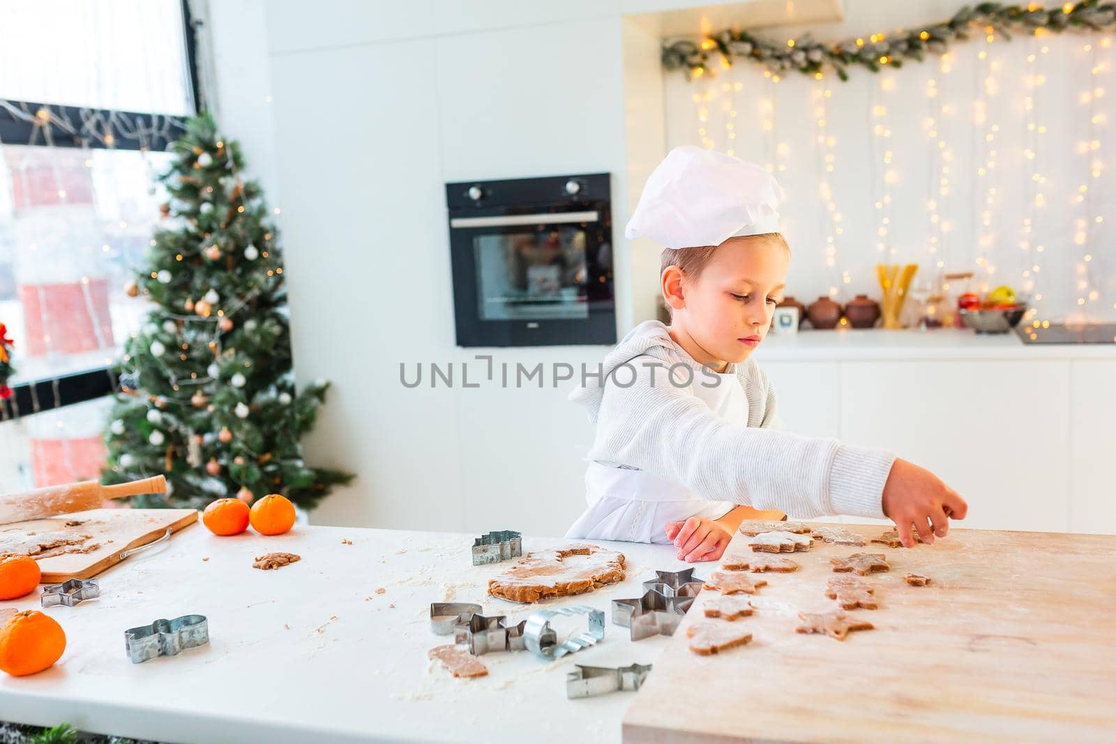 Cute little boy making gingerbread, cutting cookies of gingerbread dough. Christmas bakery. Festive food, cooking process, family culinary, Christmas and New Year traditions concept