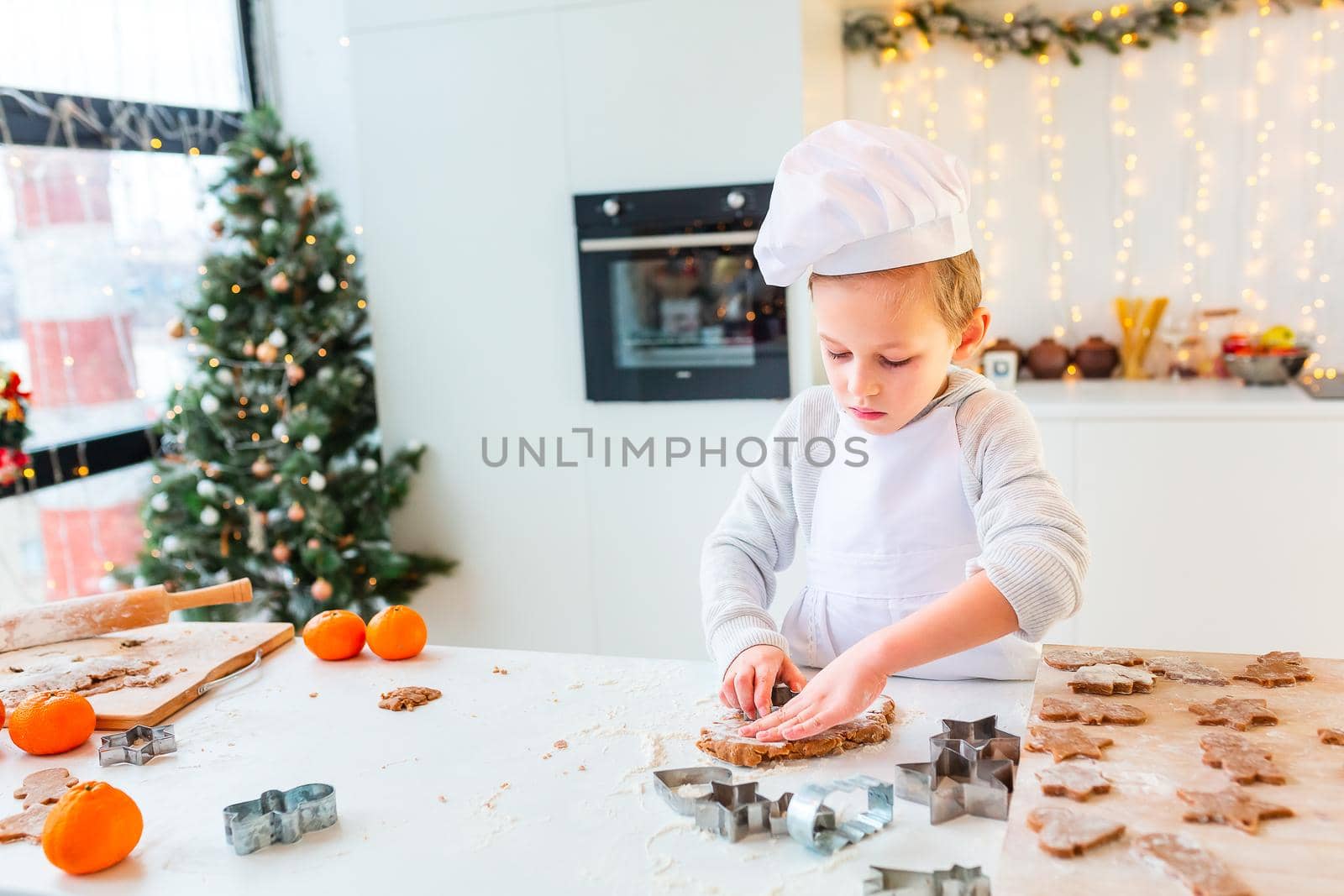 Cute little boy making gingerbread, cutting cookies of gingerbread dough. Christmas bakery. Festive food, cooking process, family culinary, Christmas and New Year traditions concept