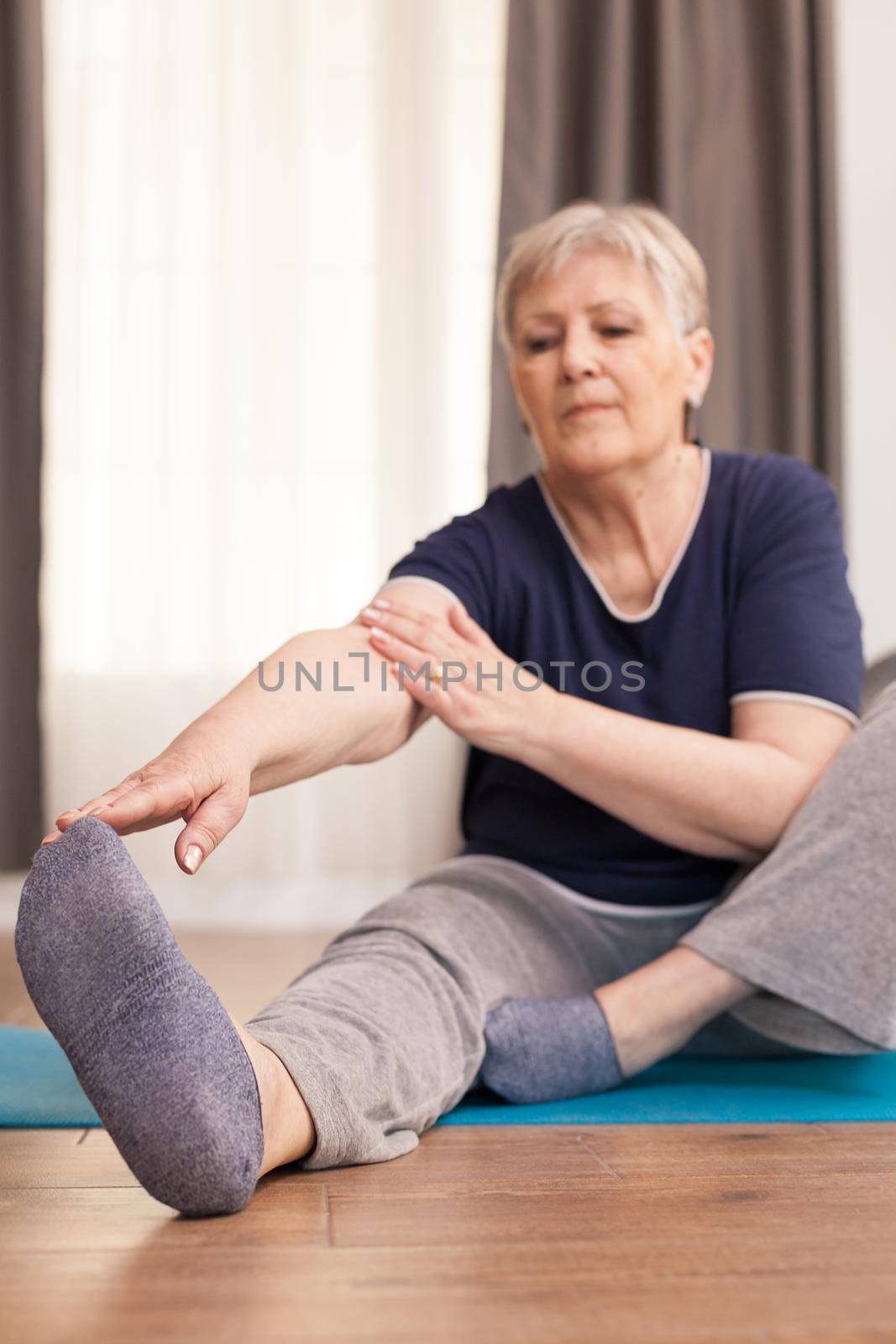 Senior woman doing recovery exercises at home, in living room. Old person pensioner online internet exercise training at home sport activity with dumbbell, resistance band, swiss ball at elderly retirement age