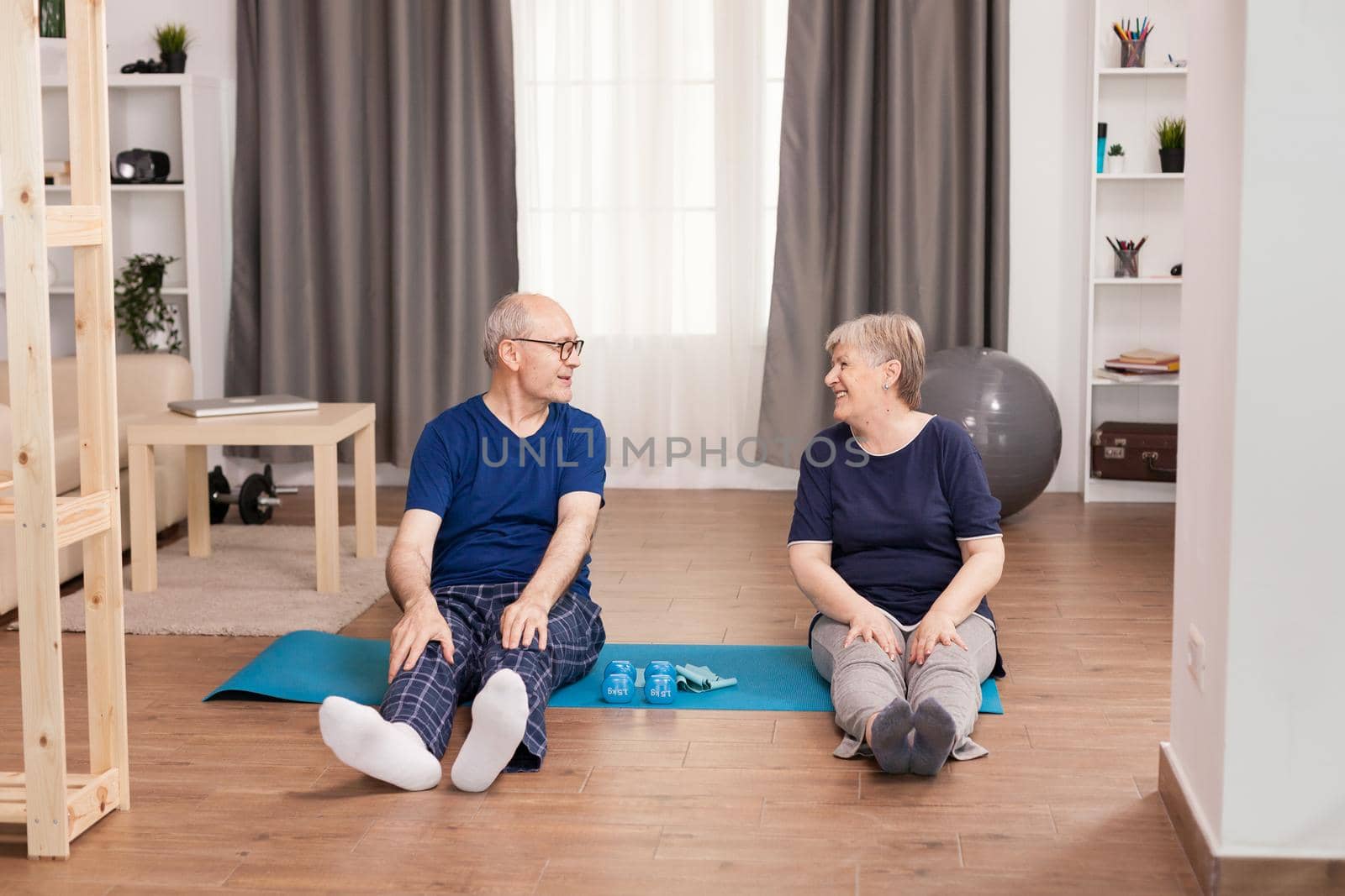 Old couple having fun doing sport in living room. Old person healthy lifestyle exercise at home, workout and training, sport activity at home on yoga mat.