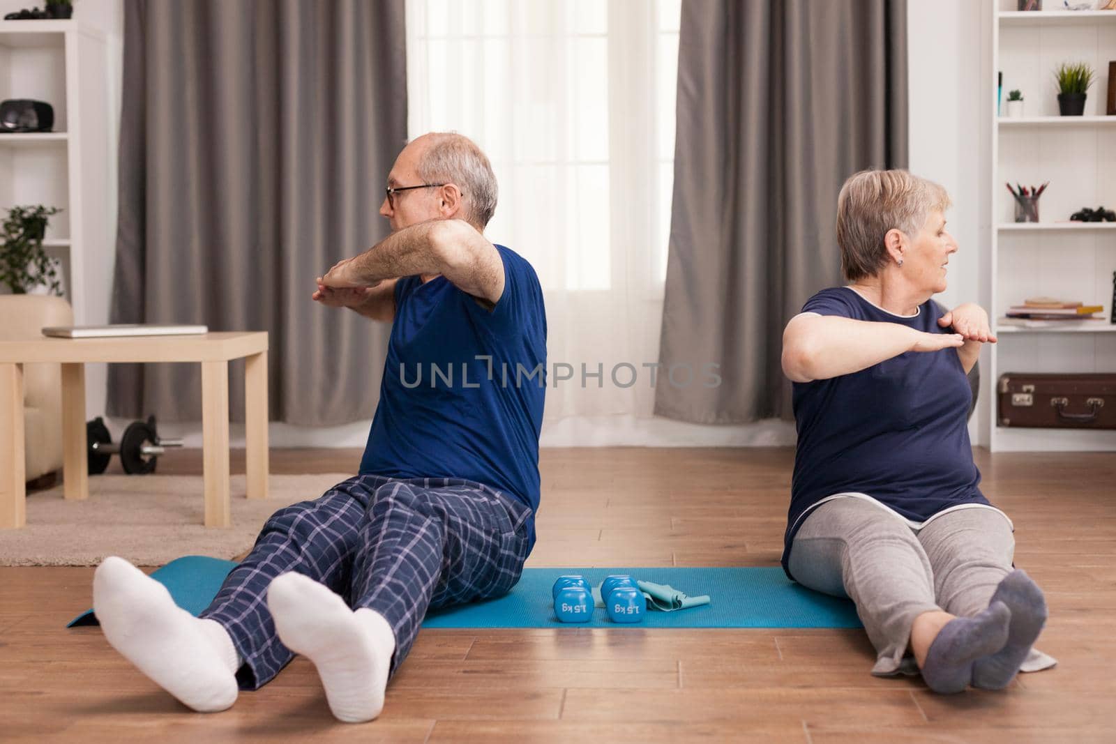 Exercises for elderly health at home on yoga mat. Old person healthy lifestyle exercise at home, workout and training, sport activity at home on yoga mat.