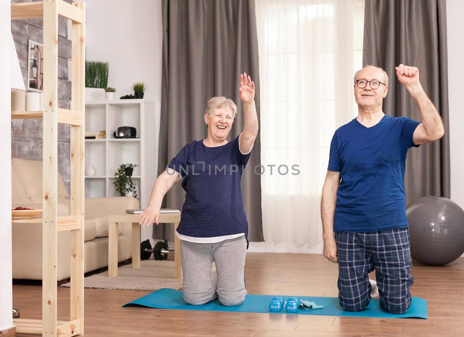 Active couple working on toning the arms. Old person healthy lifestyle exercise at home, workout and training, sport activity at home on yoga mat.