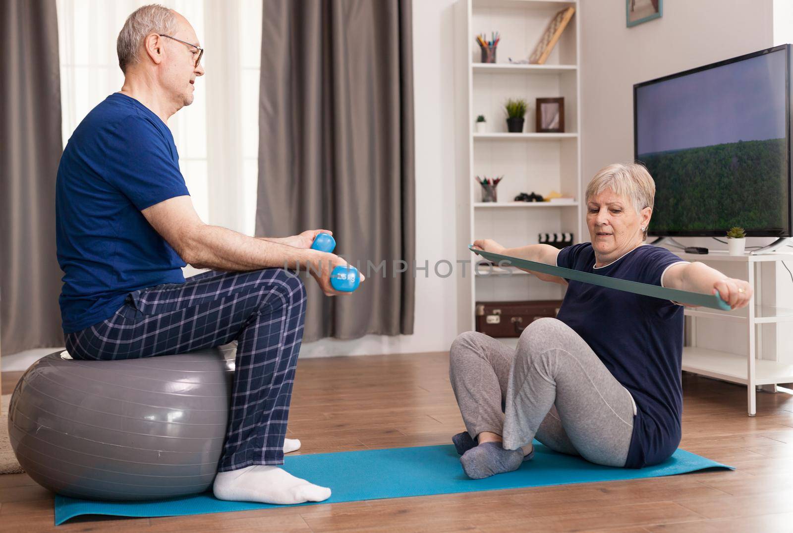 Older couple training each other for a healthy life. Old person healthy lifestyle exercise at home, workout and training, sport activity at home on yoga mat.