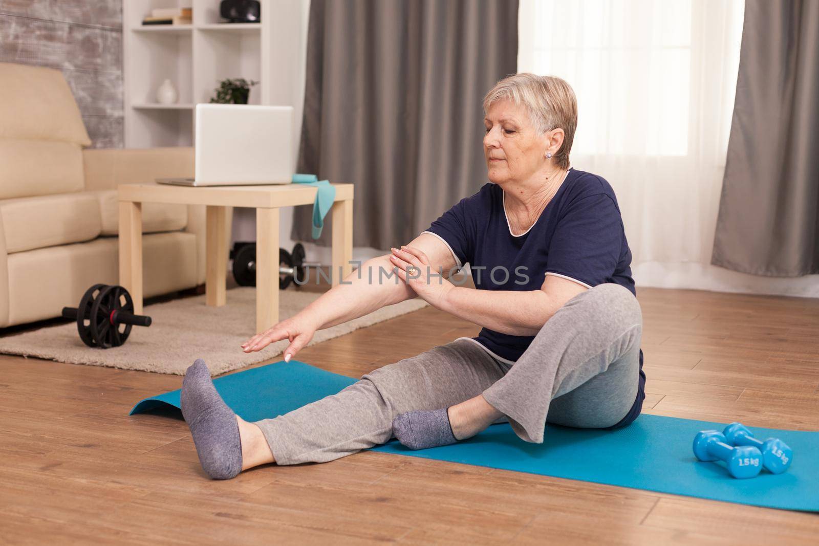 Senior healthy woman practicing fitness at home. Old person pensioner online internet exercise training at home sport activity with dumbbell, resistance band, swiss ball at elderly retirement age