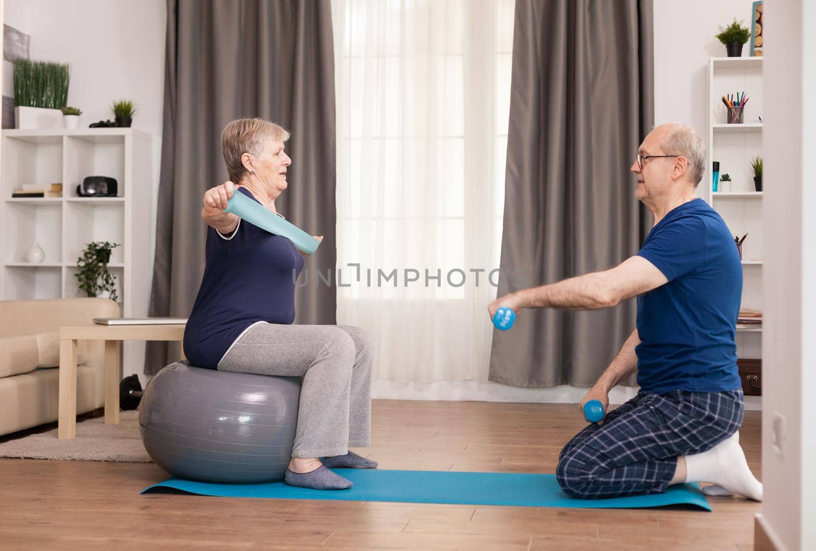 Cheerful senior couple training together on yoga mat. Old person healthy lifestyle exercise at home, workout and training, sport activity at home.