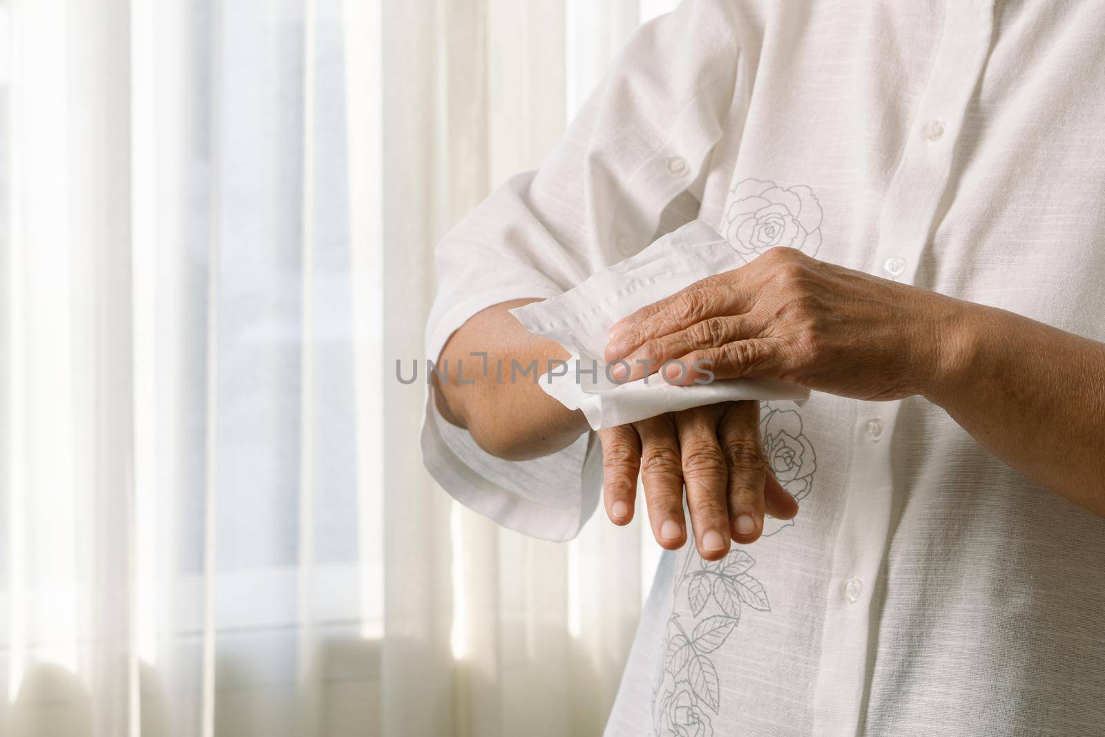 Senior woman cleaning her hands with white soft tissue paper. isolated on a white backgrounds