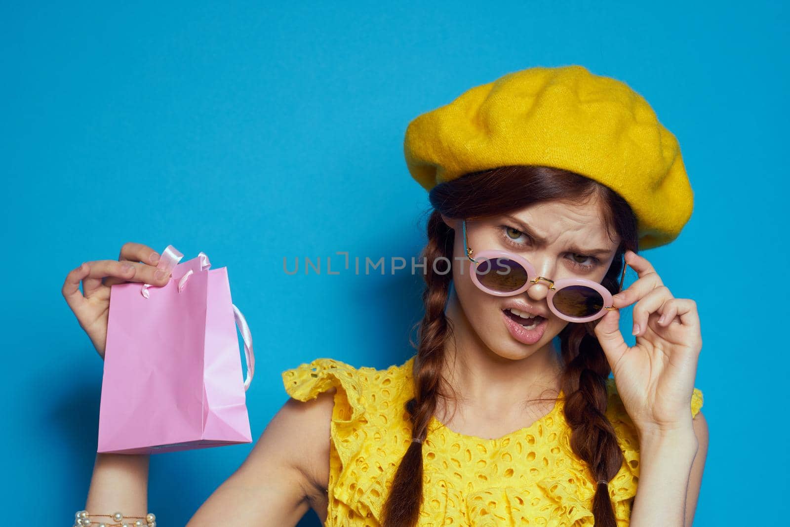 cheerful woman wearing sunglasses posing shopping fashion blue background. High quality photo
