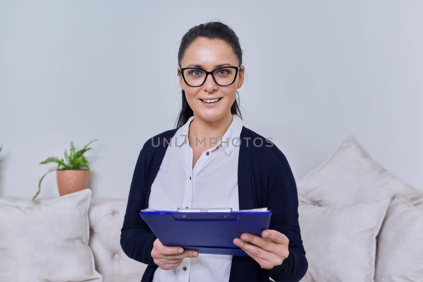 Portrait of a business woman 40 years old wearing glasses with a clipboard in her hands, smiling female looking at the camera