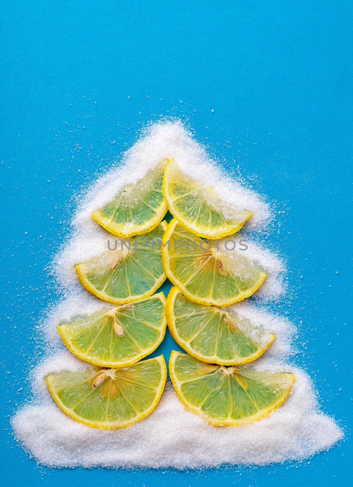 Christmas tree made from lemon and sugar fruits on a blue background.