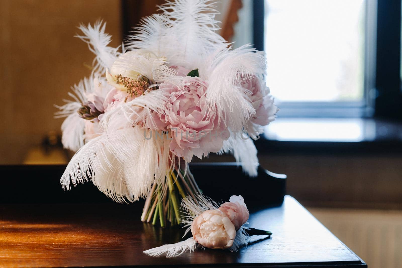 The bride's wedding bouquet of roses decorated with white feathers and a boutonniere.
