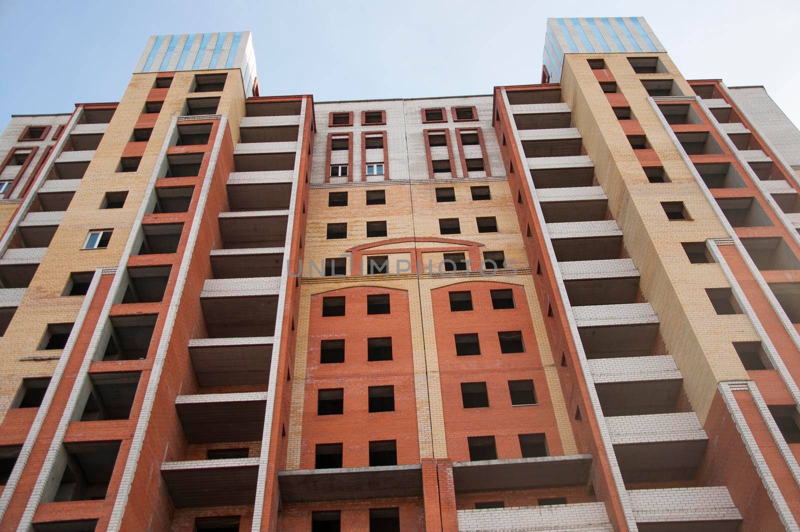 City house under construction. Unfinished multi-storey building. Uncovered facade of the building. Concrete construction is the basis for multi-family housing. Construction site in the city.