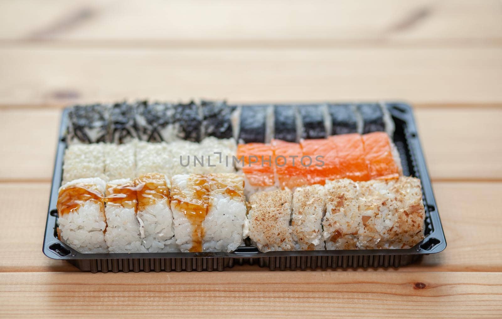 Making sushi and rolls at home. Sushi with seafood, salad and white rice. Food for family and friends. A set of different rolls and sushi on a tray.