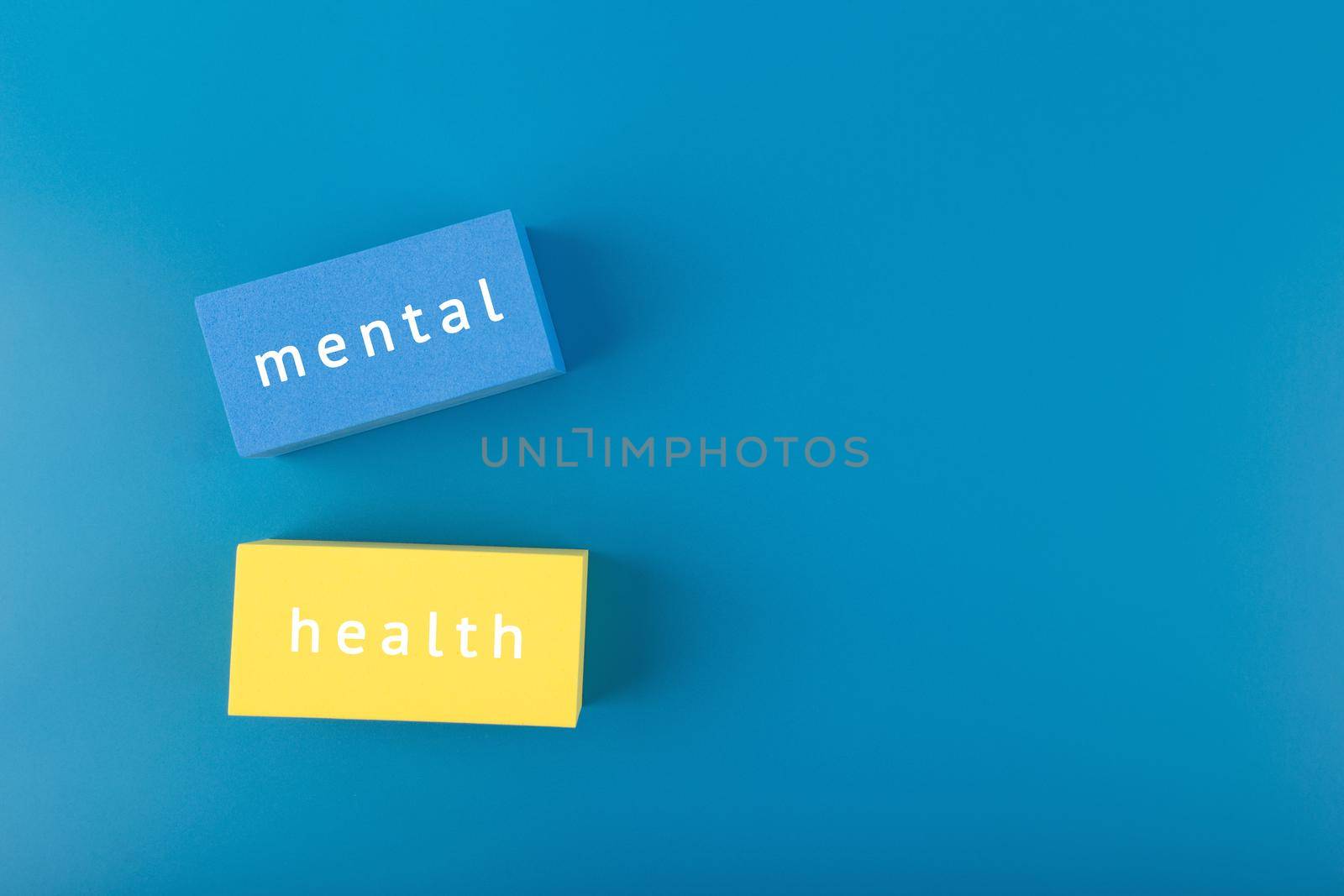 Creative flat lay with blue and yellow blocks with written mental health text on dark blue background with copy space. Concept of world mental health day, mental health assessment and awareness