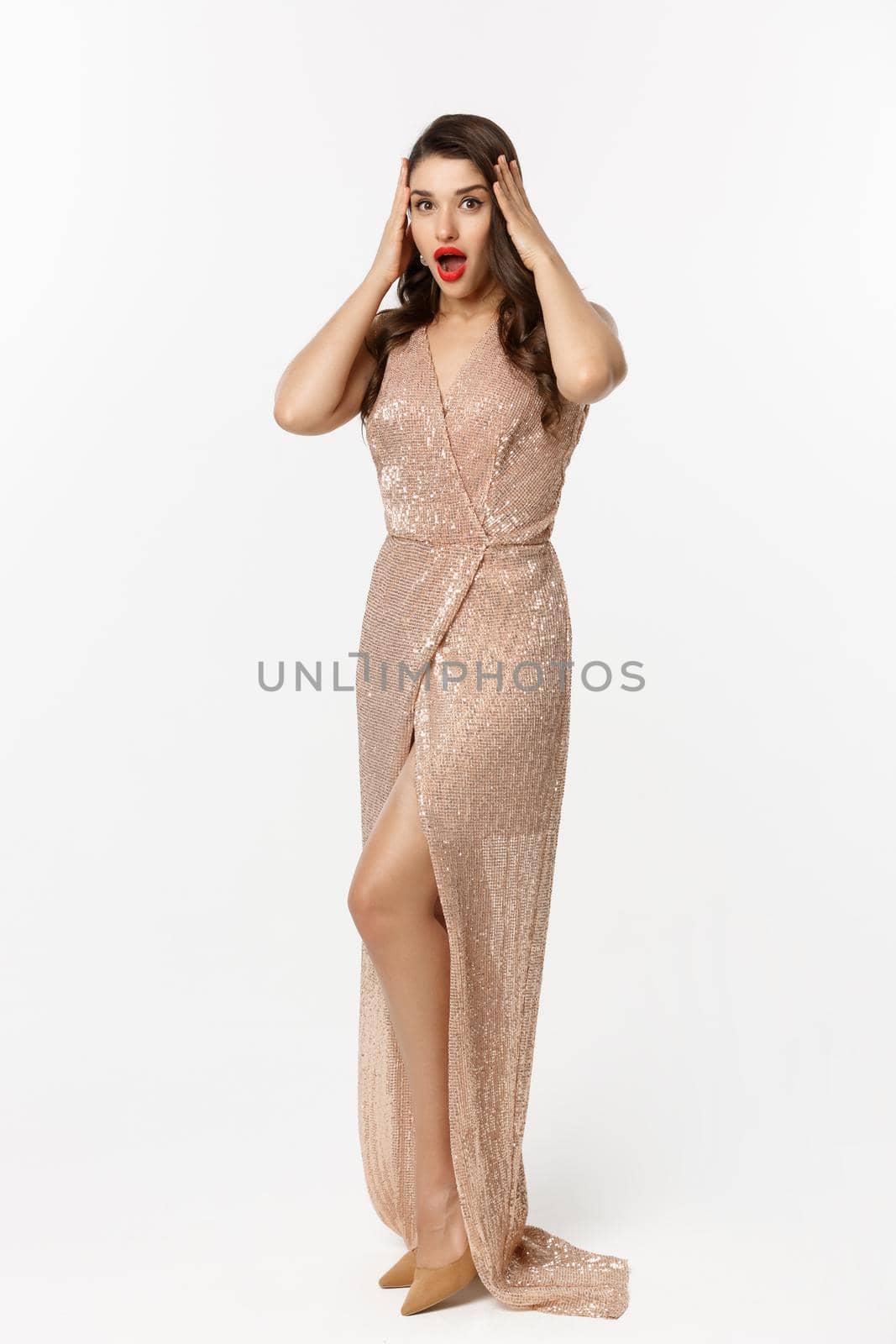 Christmas party and celebration concept. Full length of beautiful brunette woman looking surprised, wearing elegant dressed and staring with disbelief at camera, white background by Benzoix