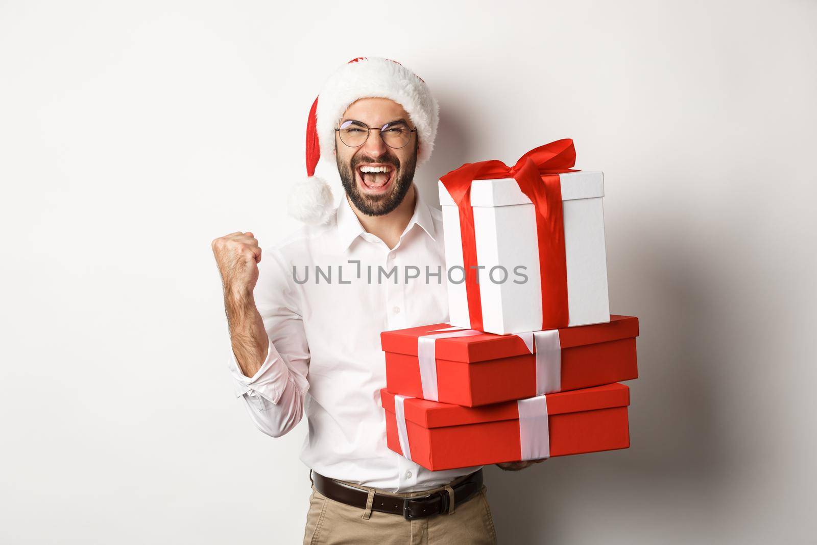 Merry christmas, holidays concept. Excited man receiving xmas gifts and rejoicing, wearing santa hat, celebrating New Year, white background.