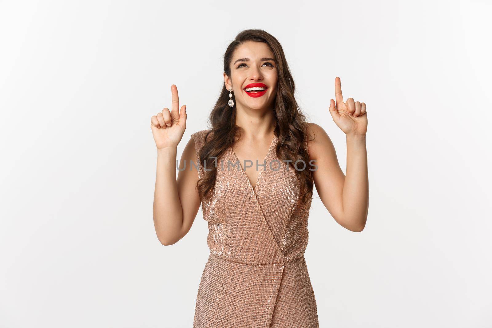 New Year, christmas and celebration concept. Happy elegant woman in party dress, laughing and looking up, pointing at top promo offer, white background.