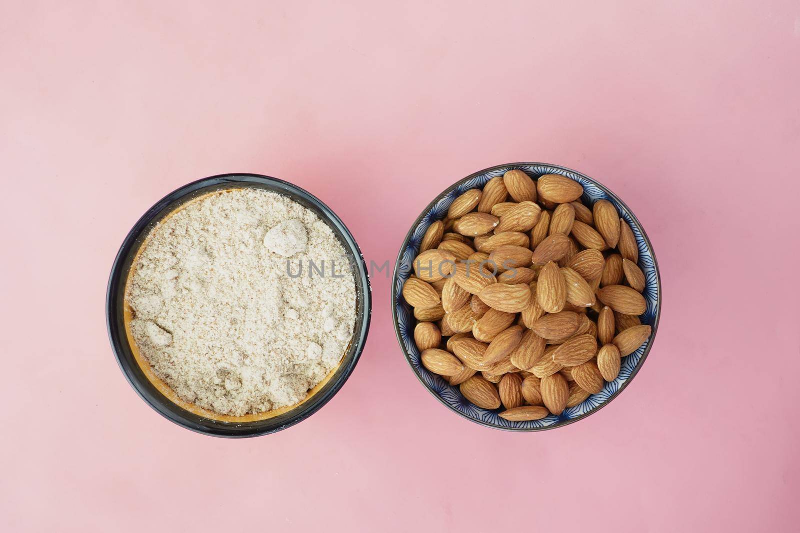 almond powder and almond in a bowl on pink .