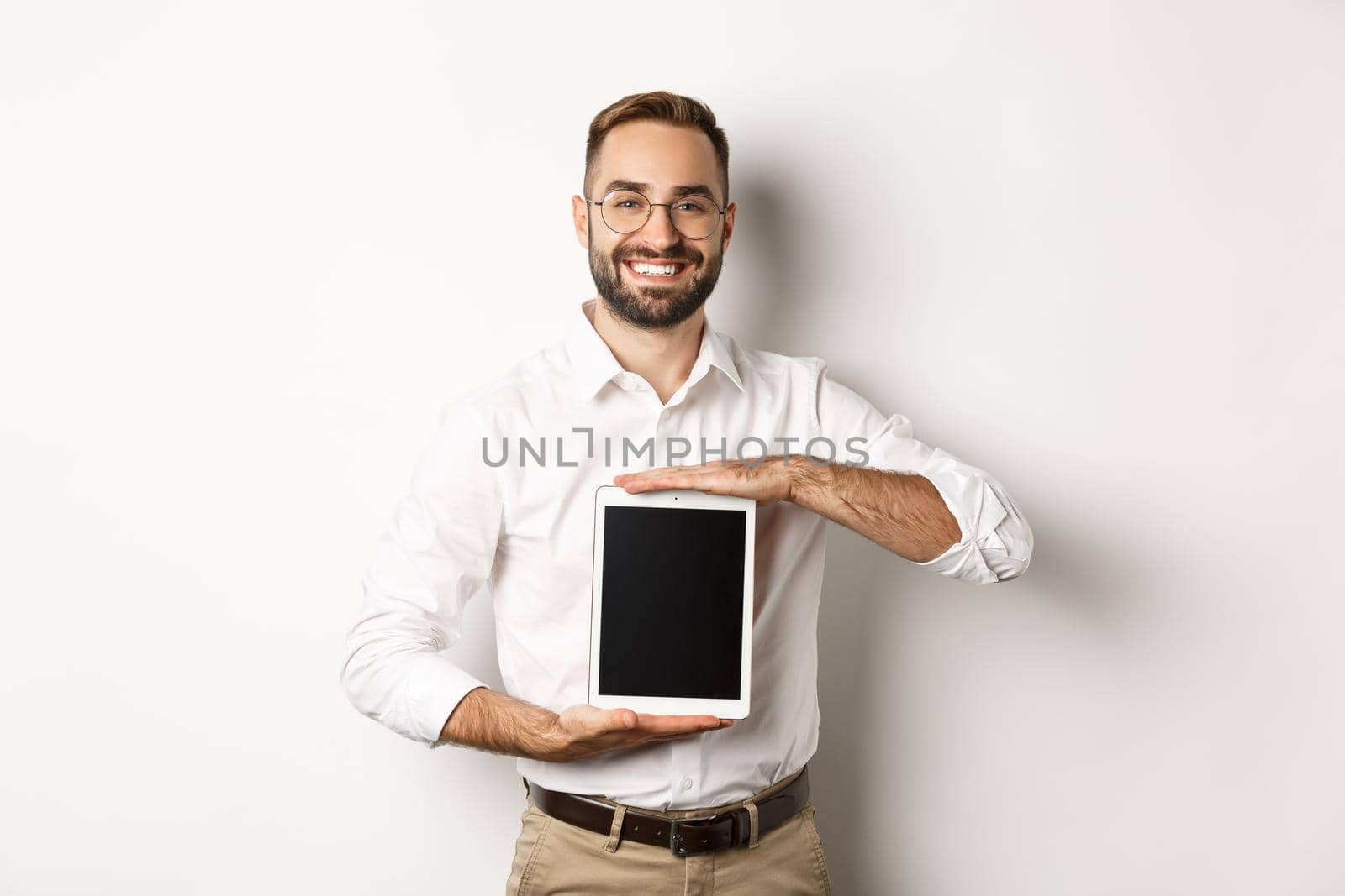 Smiling manager showing something on digital tablet screen, demonstrating website, standing over white background.