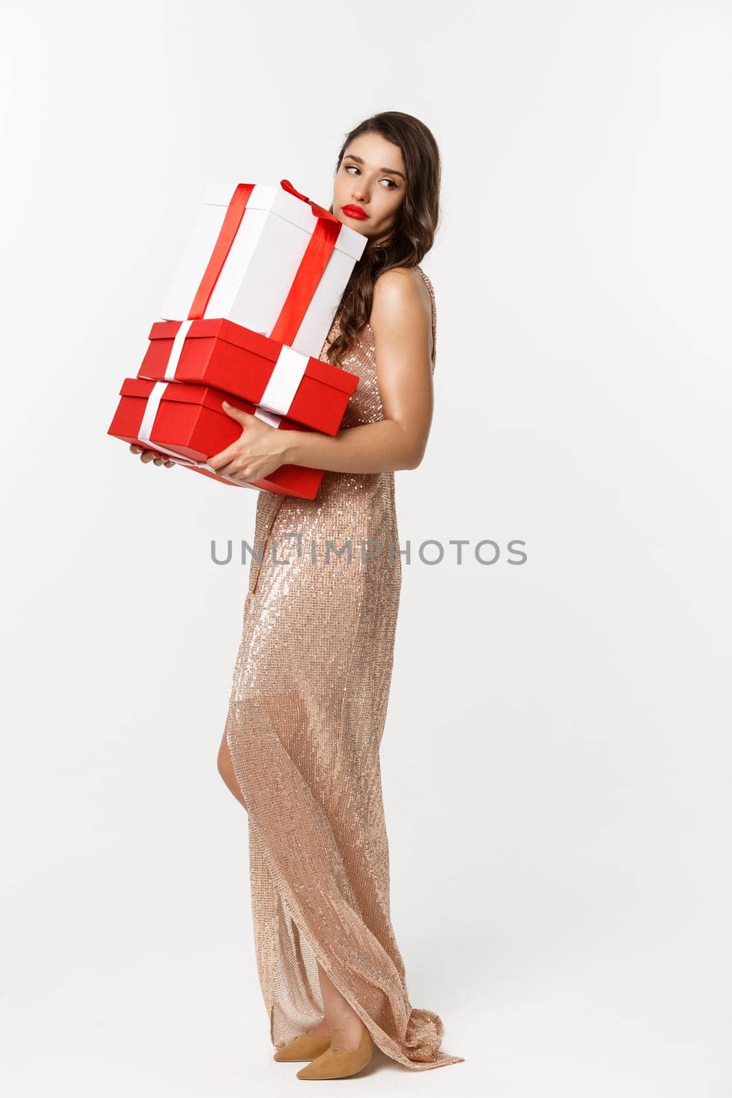 Party and celebration concept. Full-length of attractive glamour woman in elegant dress, holding Christmas gifts and looking tired, white background.