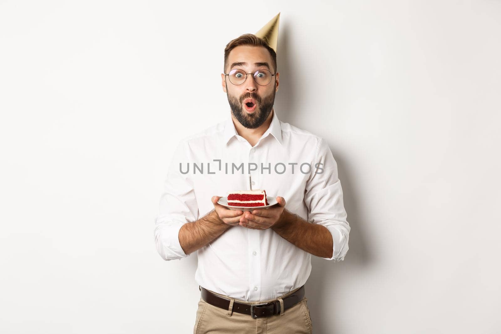 Holidays and celebration. Happy man having birthday party, making wish on b-day cake and smiling, standing against white background by Benzoix