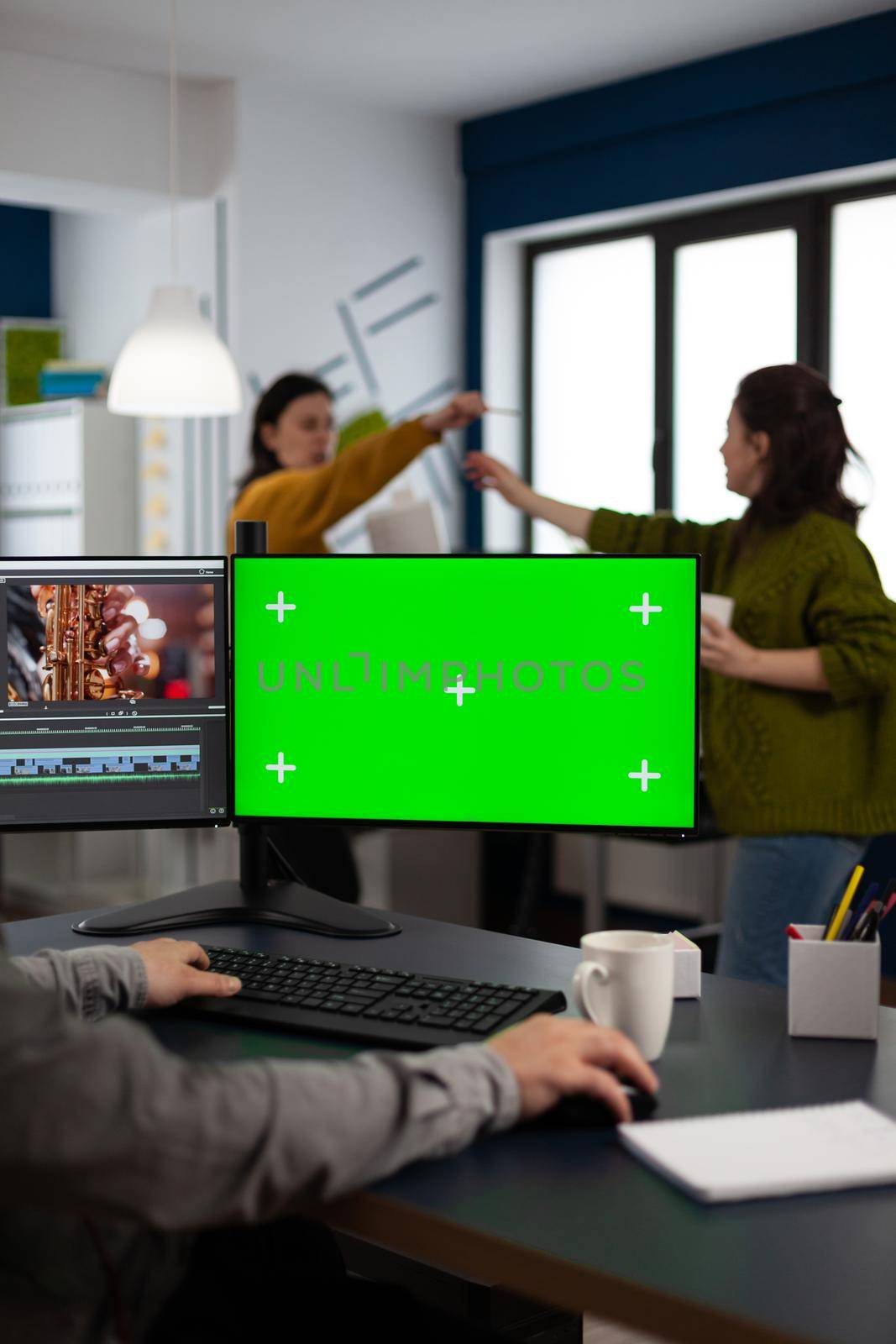 Video maker editor editing movie project using post production software working in post production agency at pc with green screen, chroma key, mock up isolated display. Man processing audio montage