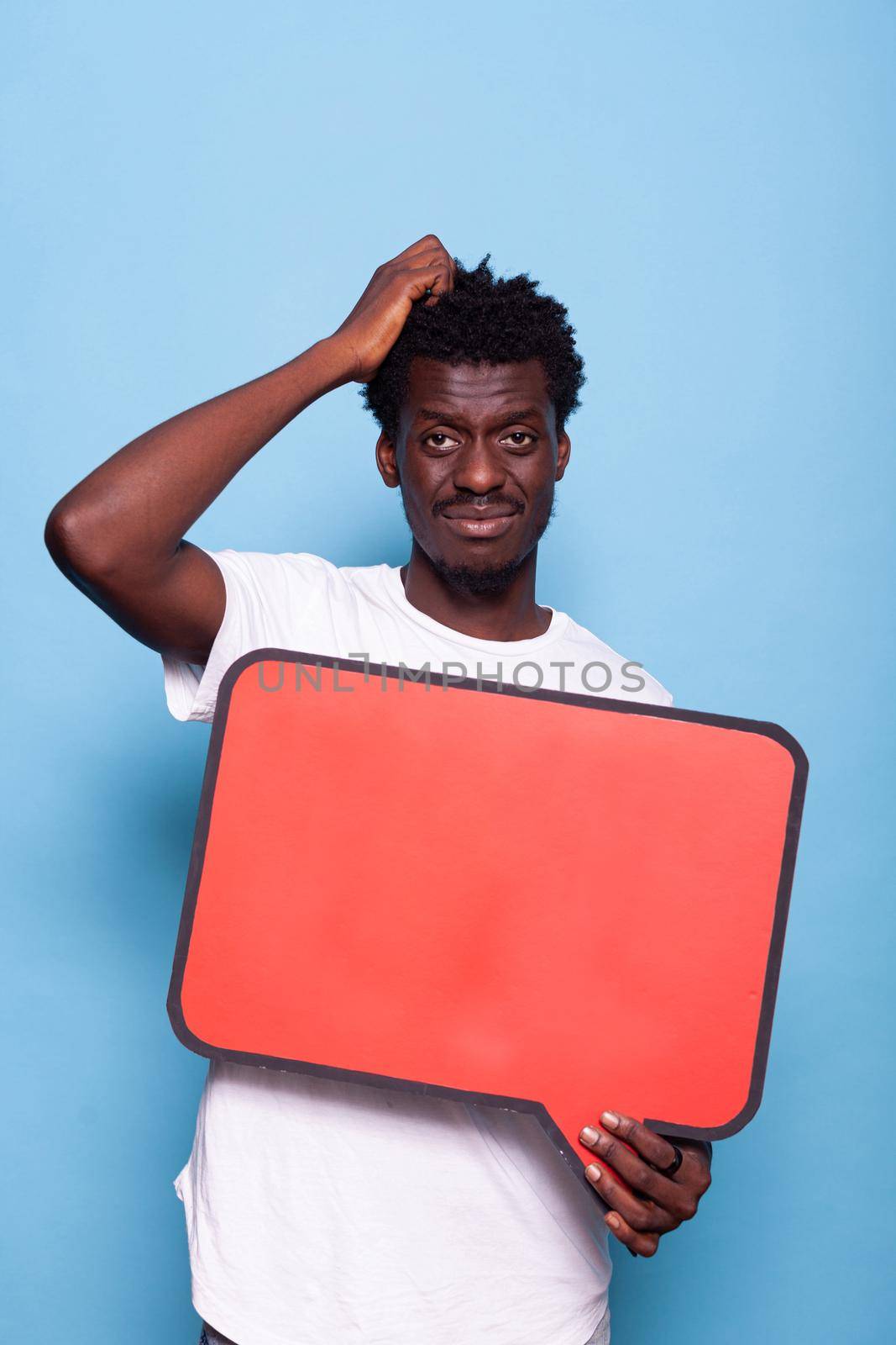 Portrait of young adult holding blank sign for communication. Person showing red speech bubble to camera, sign used for written messages and conversation. Man with board for expression