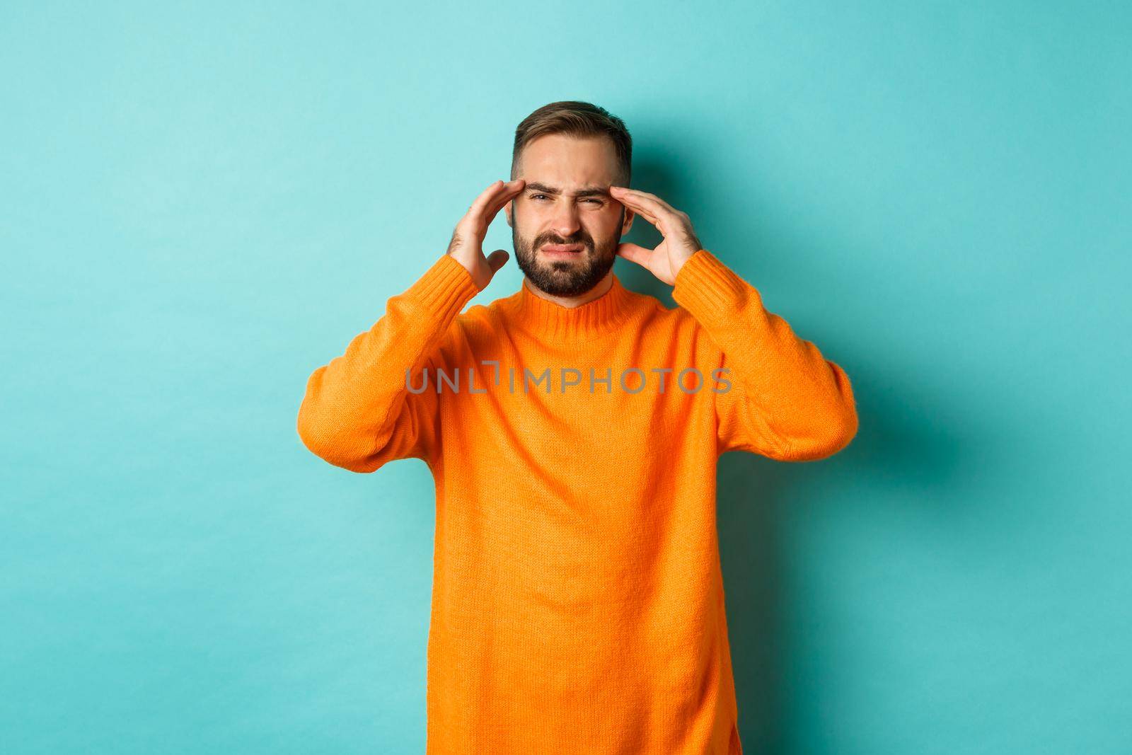 Phoro of caucasian man touching head, feeling sick, have headache or migraine, hangover after party, standing over light blue background.