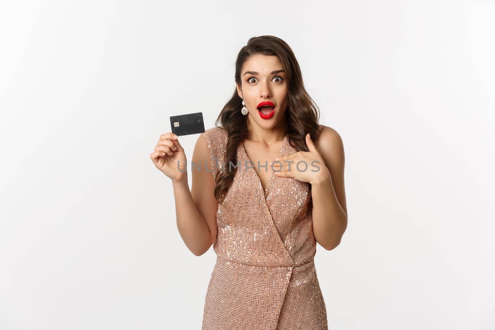 Holidays. christmas party and shopping concept. Amazed woman in stylish evening dress showing credit card, standing over white background.