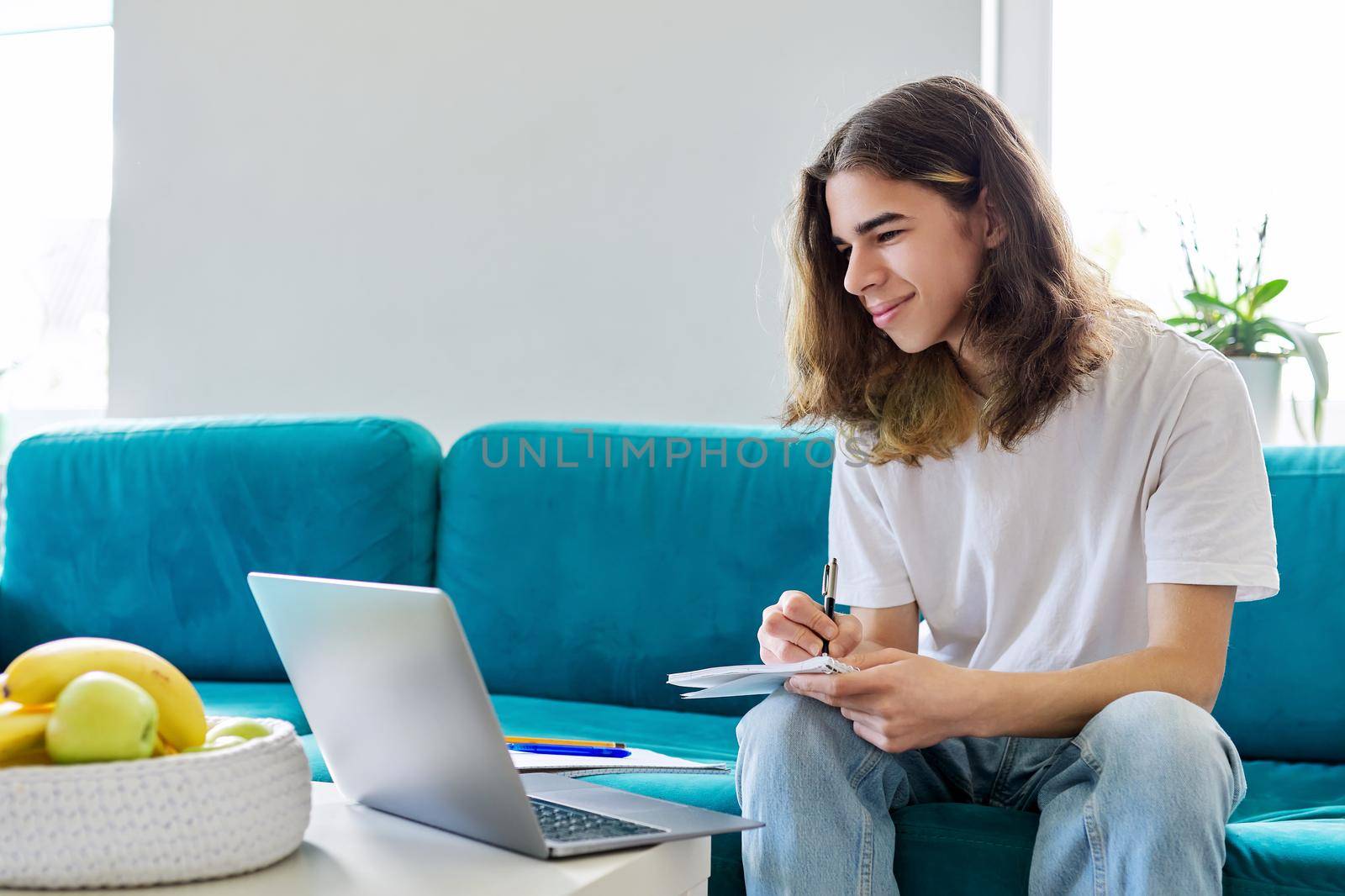 Guy student teenager studies at home online with laptop. Male 16, 17 years old sitting on couch looking at webcam talking using video call. E-learning virtual lessons digital technologies in education