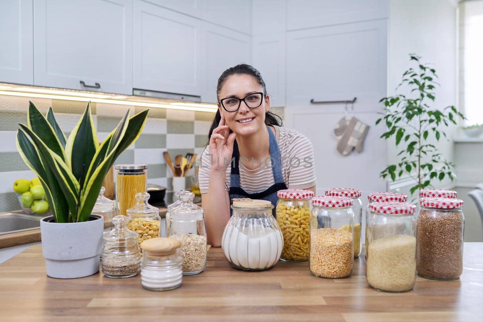 Food, grocery storage, smiling woman looking at the camera in the kitchen. by VH-studio