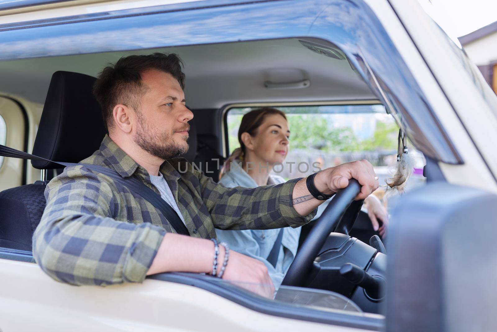 Trip, middle-aged married couple riding in the car together. Male driver, female passenger seat