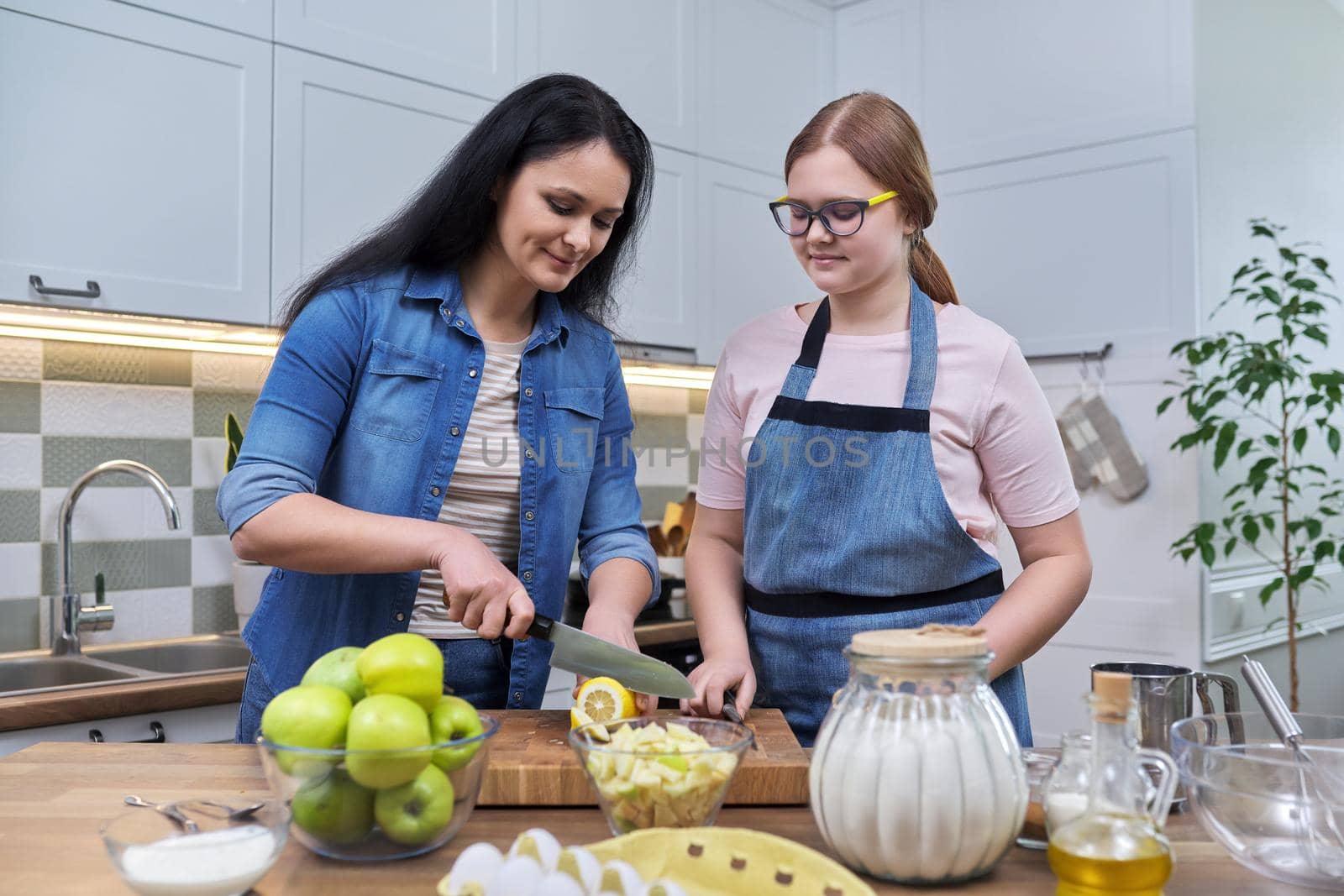 Mom and teenage daughter preparing apple pie together by VH-studio