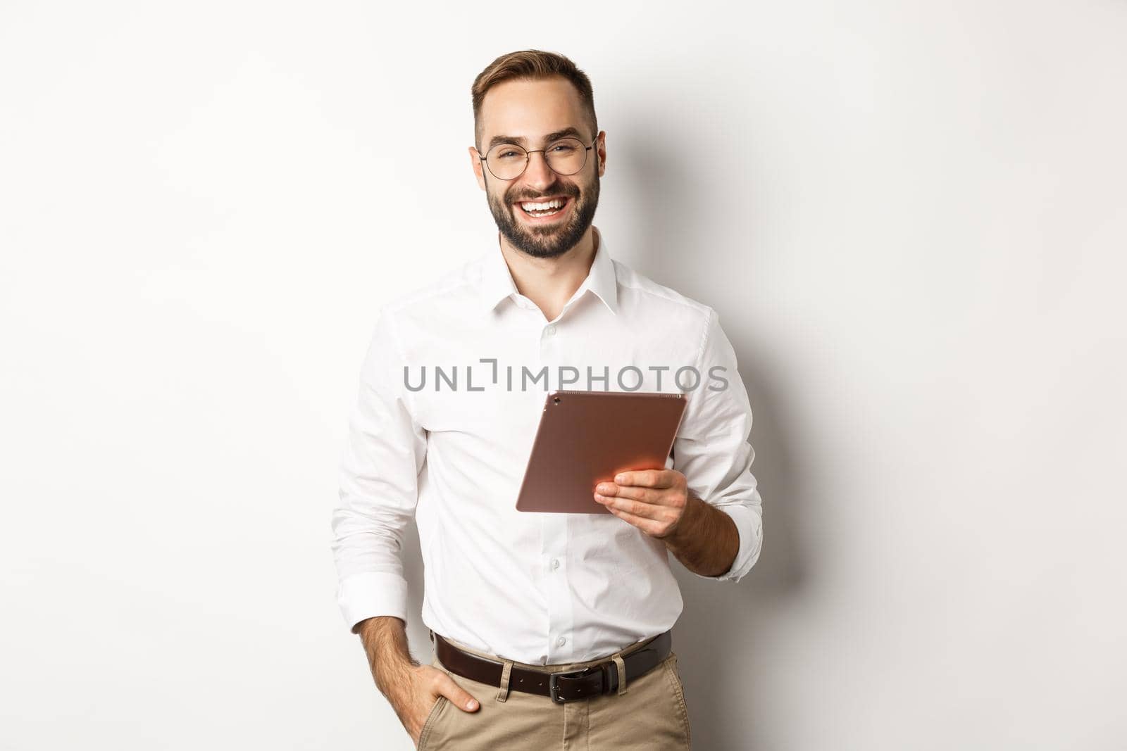 Confident business man holding digital tablet and smiling, standing against white background by Benzoix
