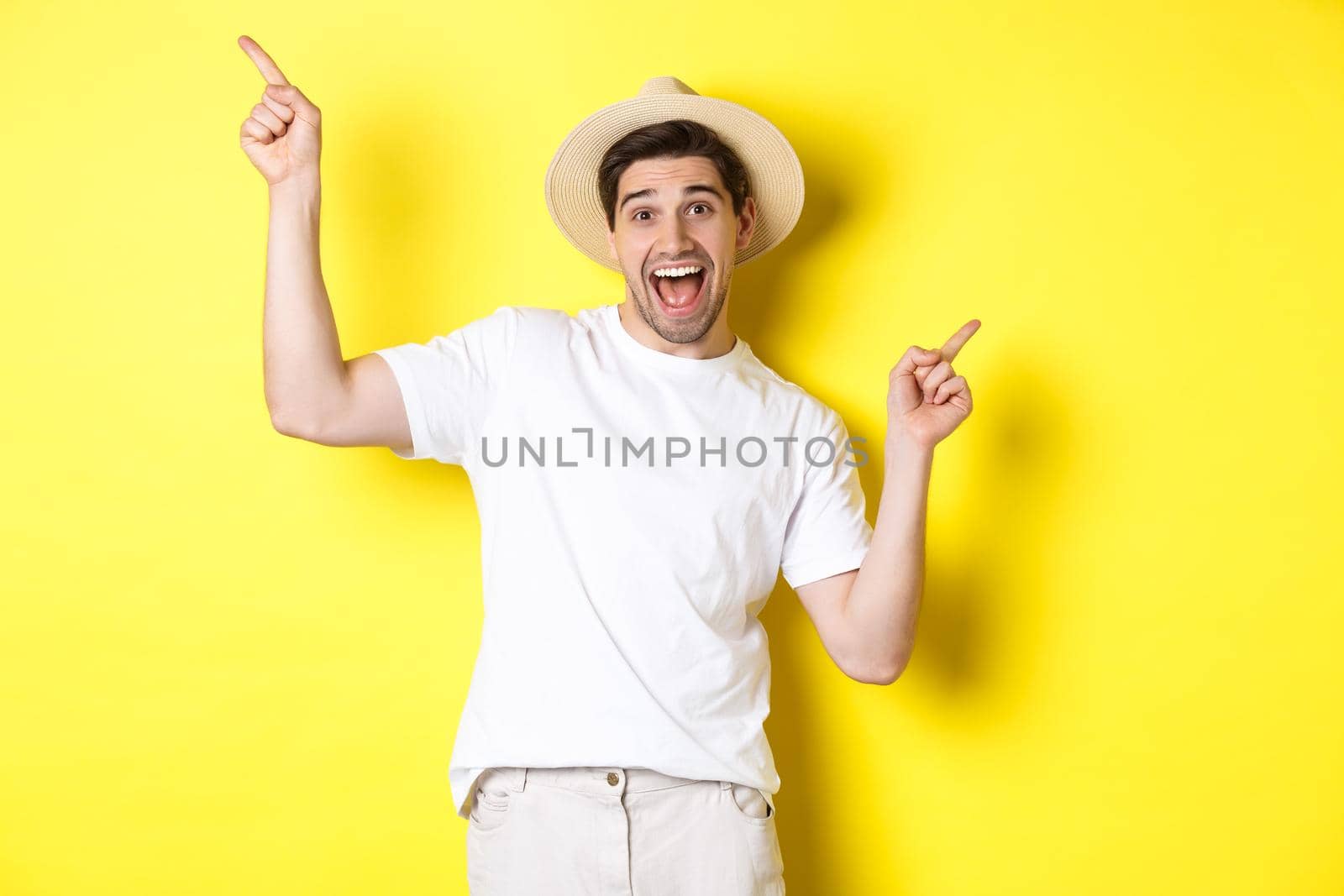 Concept of tourism and lifestyle. Happy tourist dancing and pointing fingers sideways, showing vacation variants, yellow background.