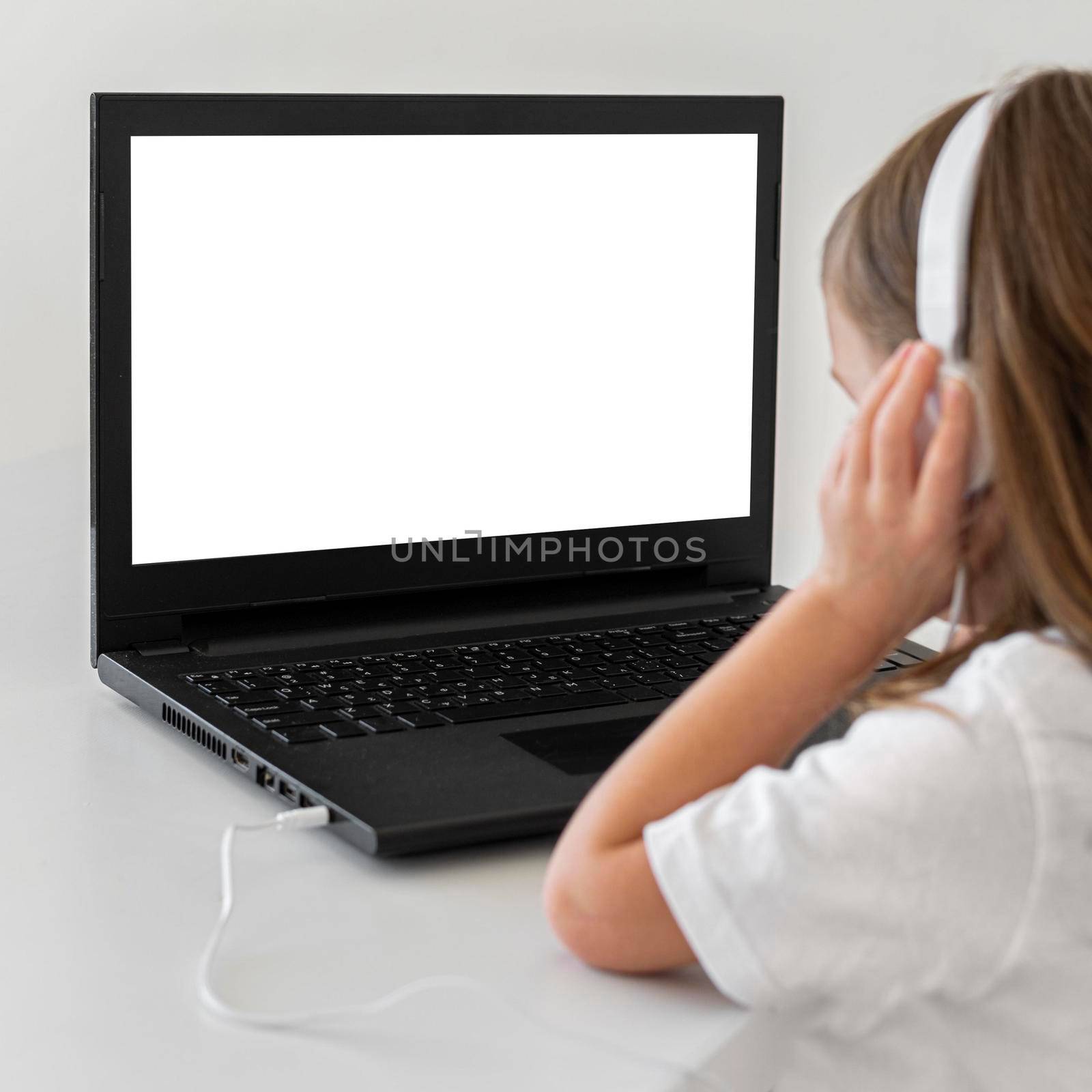 little girl using laptop with headphones. High resolution photo
