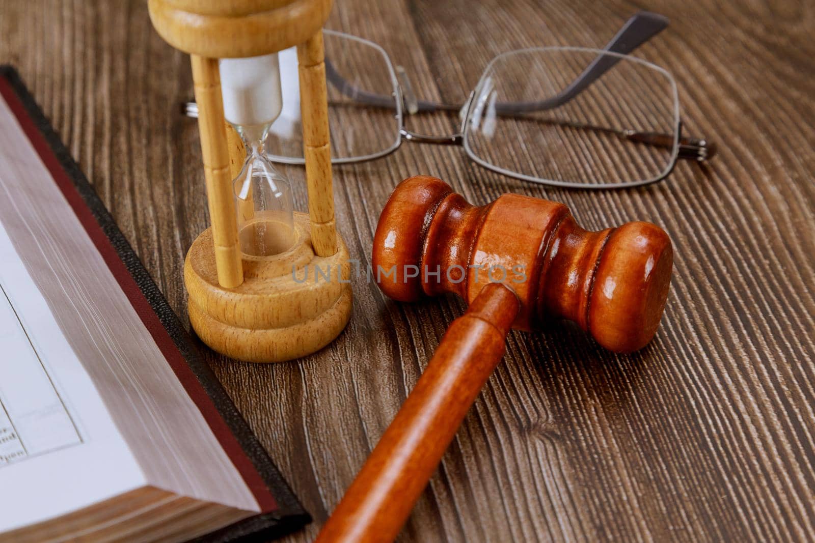 Open Bible Book with hourglass judge's gavel on wooden background by ungvar