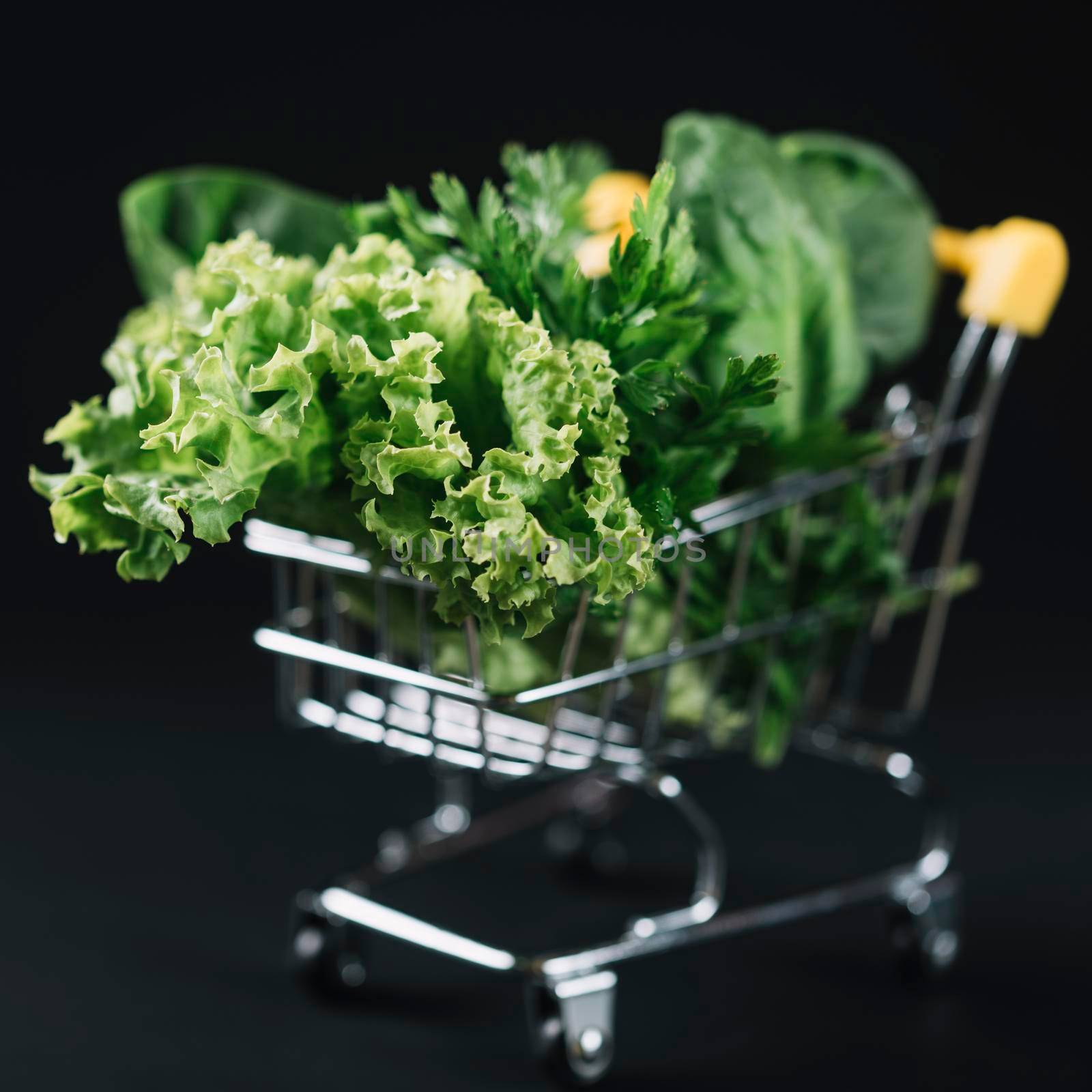 close up green leafy vegetables shopping cart black backdrop. High resolution photo