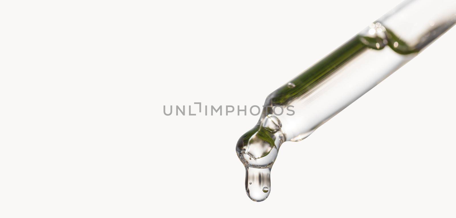 Cosmetic pipette with essential oil dropping, serum with peptides, hyaluronic acid on white background. Closeup of blue dropper, falling drop close up. Self care concept. by photolime