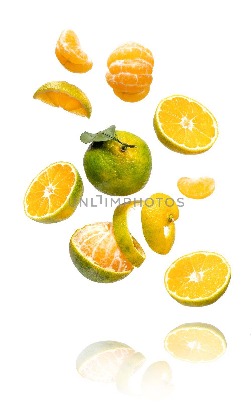 Fresh ripe green mandarine with leaf falling in air. Cut, peeled, slices and whole green tangerine isolated on white background with clipping path. Food levitation concept